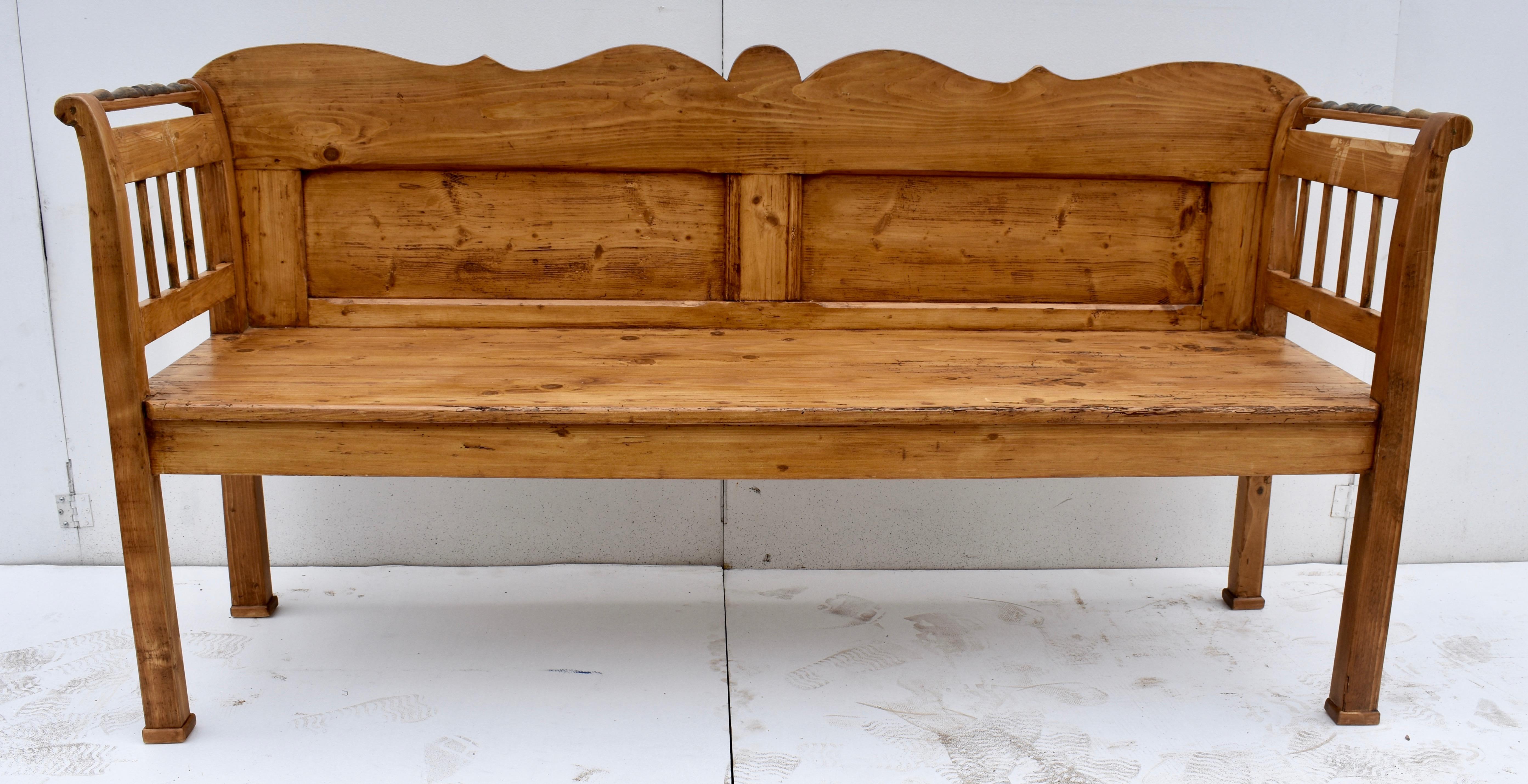 A little unassuming at first, this bench is distinguished by a few unusual features. The back rails and stiles, with a boldly scalloped top rail, frame two rectangular flat panels, the whole assembly attaching to the back of the integral arms and