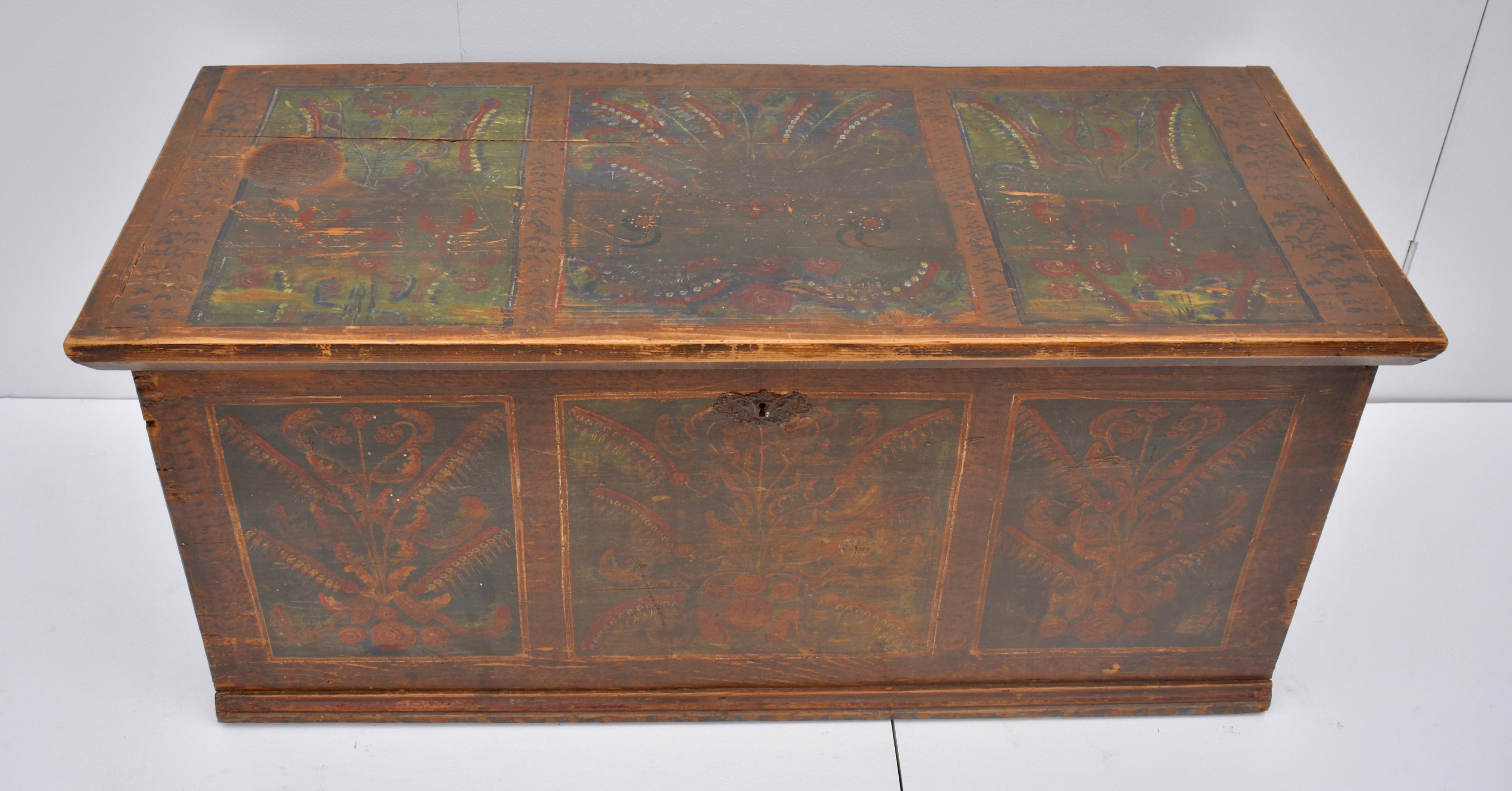 The background of this Primitive, nailed, hand painted trunk is a stylized grain paint. The sides have no further decoration. The front bears three painted panels enclosing multicolored bouquets of flowers and ferns on green, contrasting nicely with