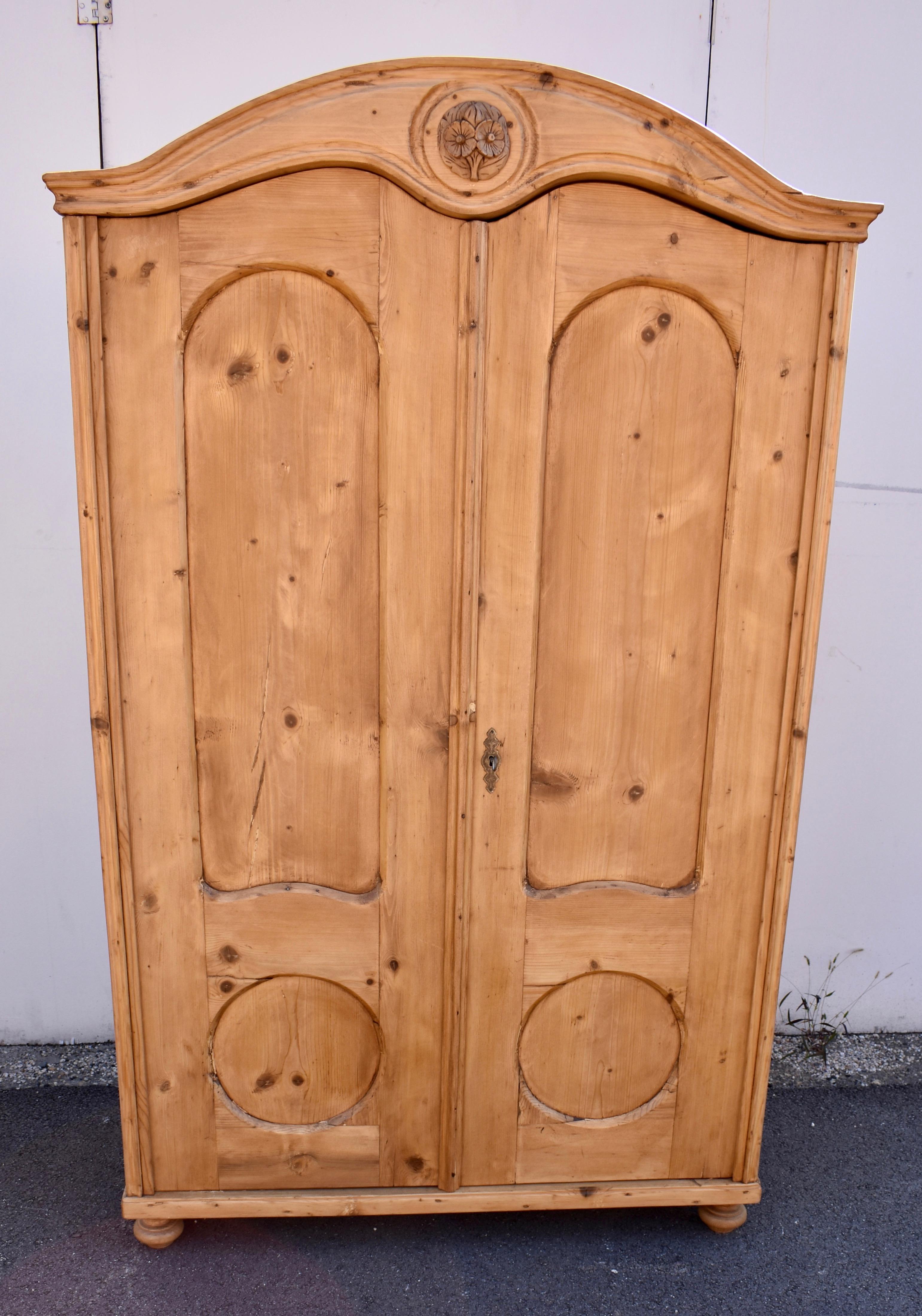 This is an interesting two door armoire with a very attractive form.  It is very similar to another listed here.  The bonnet-top crown has a wonderful “swooping” line on top with a Queen Anne style double arch beneath.  In the center of the crown is