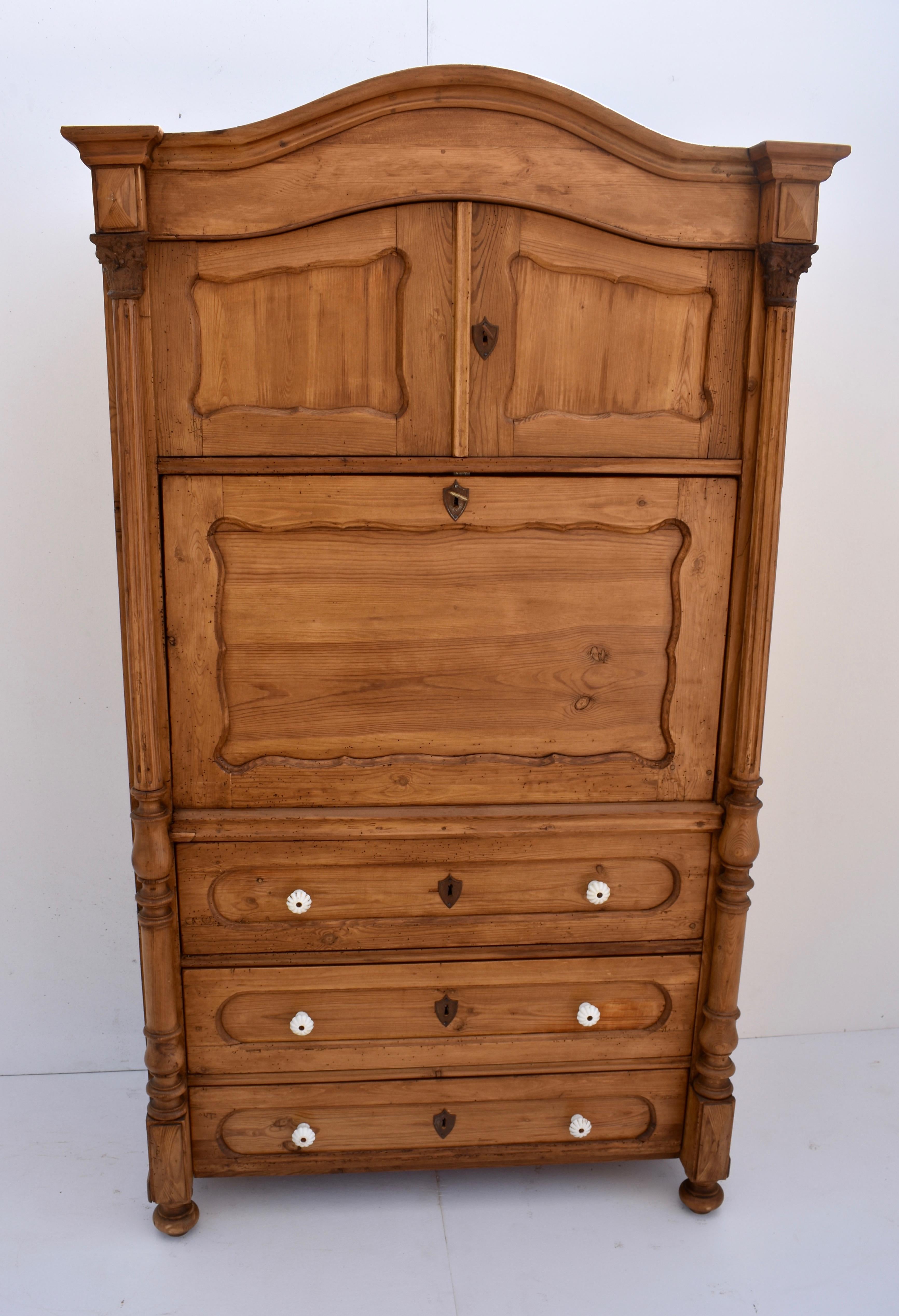 This is an outstanding Dutch pine secretaire a abatant from the late nineteenth century. Hardwood crown molding and a deep fascia sit above two arched paneled doors enclosing a deep storage cupboard The desk top opens to a mahogany-veneered interior