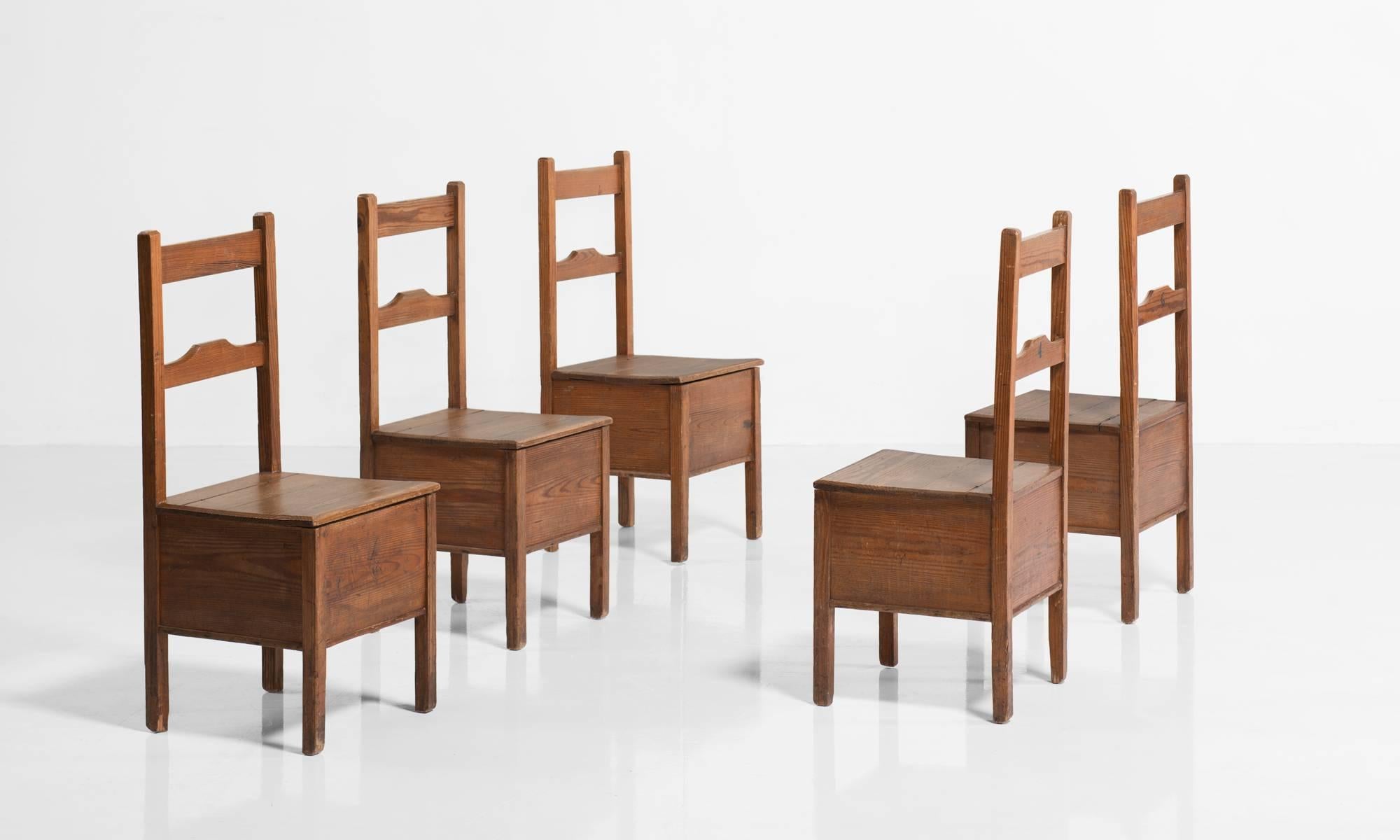 Pine box seat chairs, England, circa 1880.

Each chair is numbered on the back, and has storage underneath the seat.