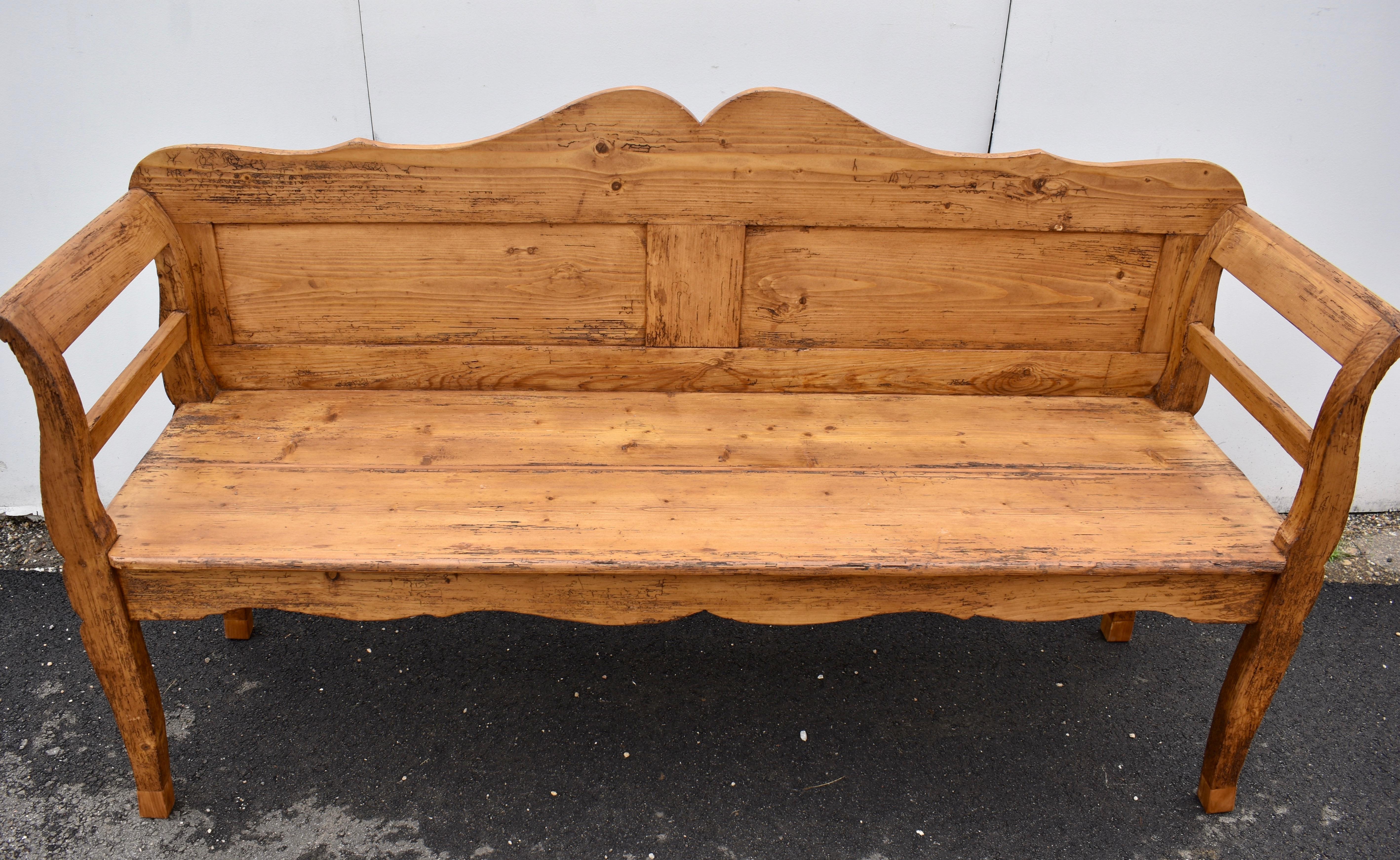 This bench has the classic lines we like to see in a Central European bench or settle. The back top rail is boldly scalloped and with the bottom rail encloses two rectangular flat panels. All four legs are nicely shaped and the integral arms have a