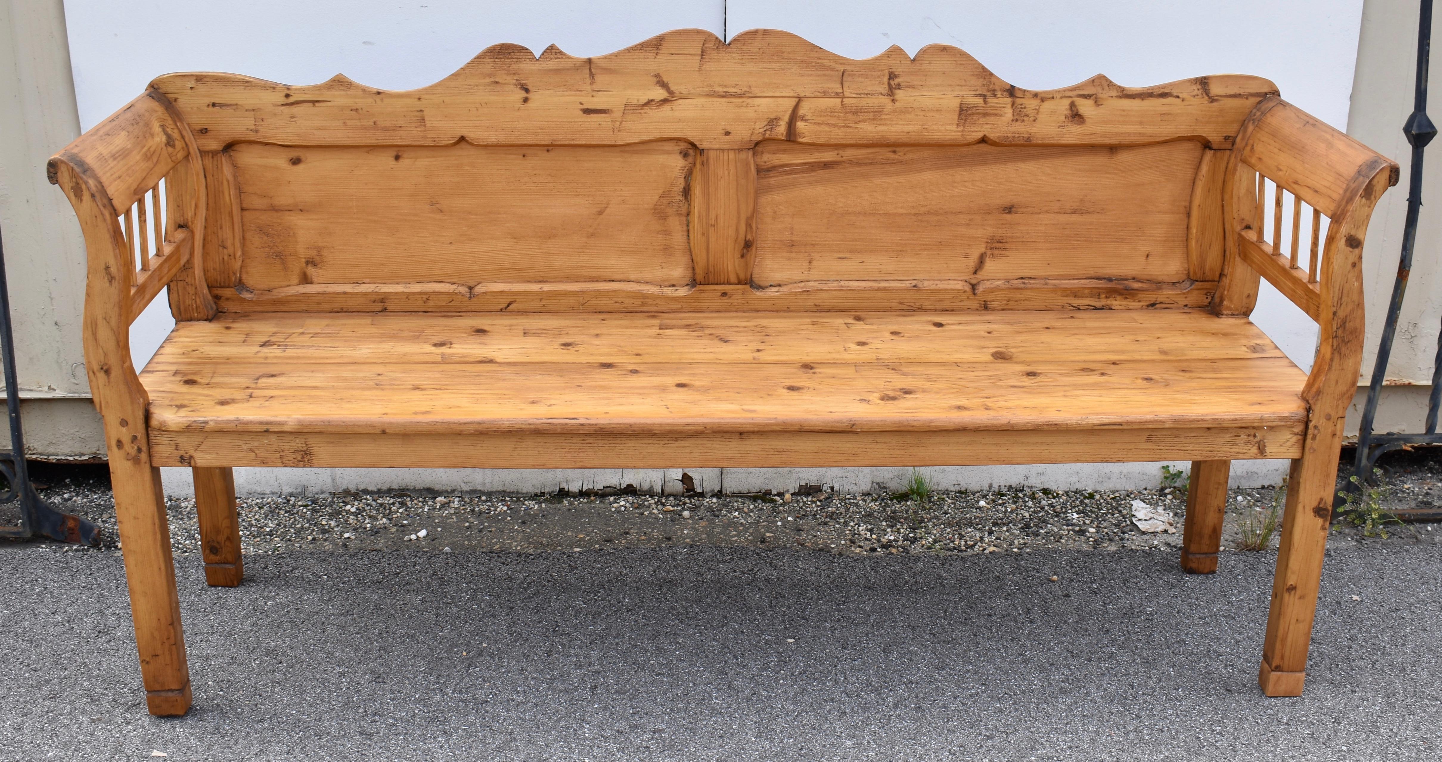 This is a lovely Camel-Back Settle.  The nicely scalloped top rail peaks with a double hump in the center and with the bottom rail forms a shapely frame for two flat panels.  The legs are straight up to seat level.  Above that the integral arms are