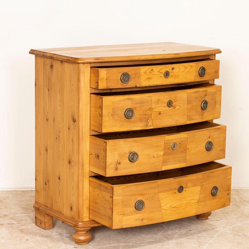 The gentle bow front of this 4-drawer chest adds to the simple grace of the piece. It has been given a waxed finish, bringing out the warmth of the wood. A pine chest of drawers such as this were typical coming of age gifts to a young woman in the