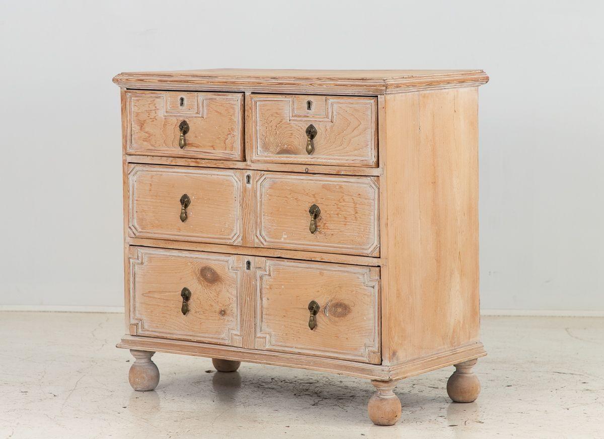 A white-washed pine chest of drawers or dresser from the 1860s exudes timeless English charm. This exquisite piece features meticulous craftsmanship, with delicately applied moldings that adorn its surface, creating an intricate play of light and