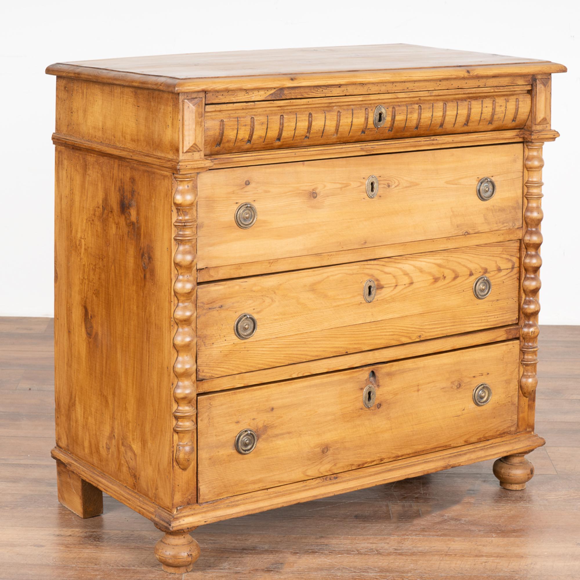 This lovely pine chest of four drawers has decorative half-column details accenting the sides and topped by traditional vertical carving along the upper drawer.
Note the natural wax finish that brings out the warmth of the pine. 
Restored, this
