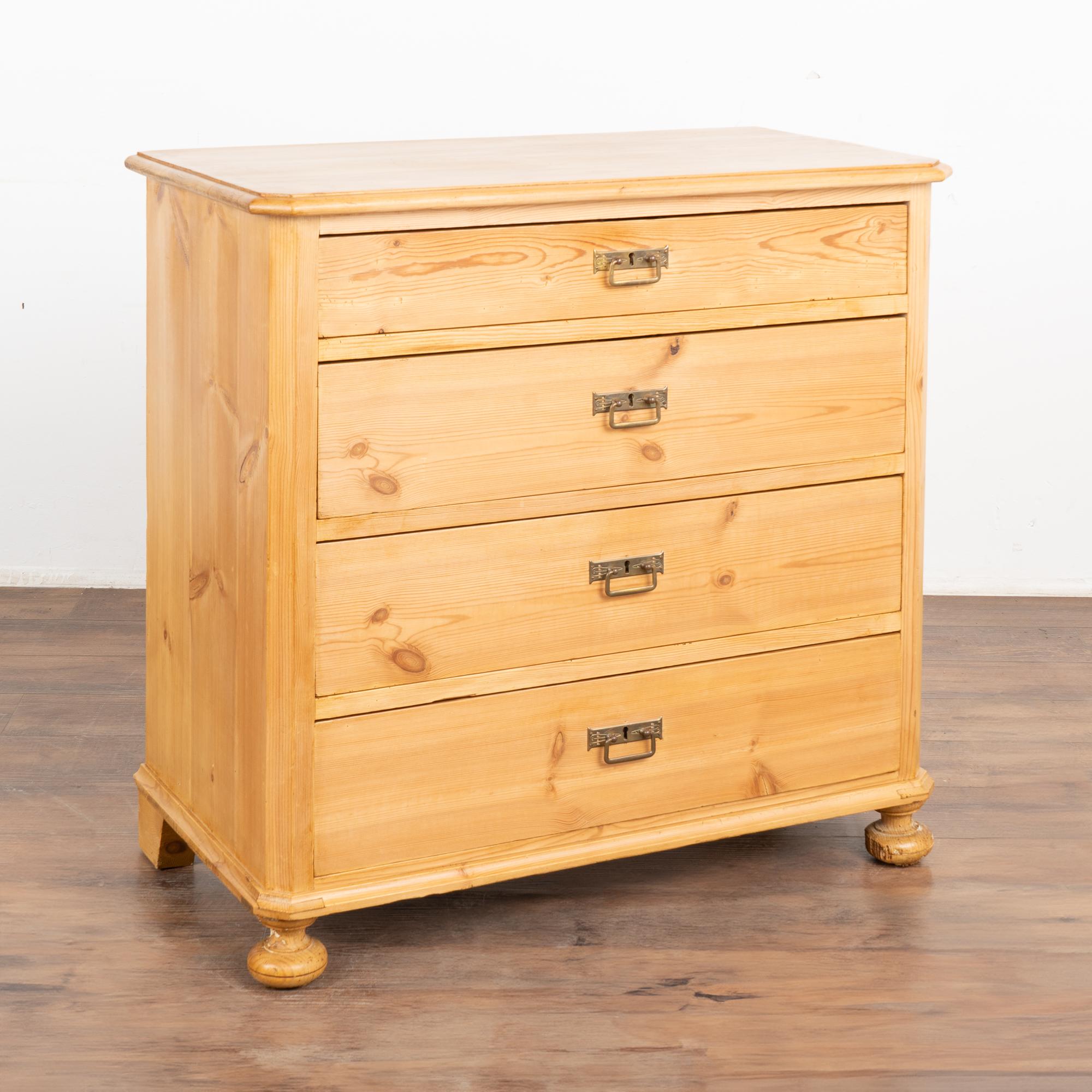 Antique pine chest of four drawers resting on bun feet.
Simple clean lines, dove-tail joints and brass pulls.
Note the natural wax finish that brings out the warmth of the pine. 
Restored, this dresser is strong, stable and ready for use. Drawers