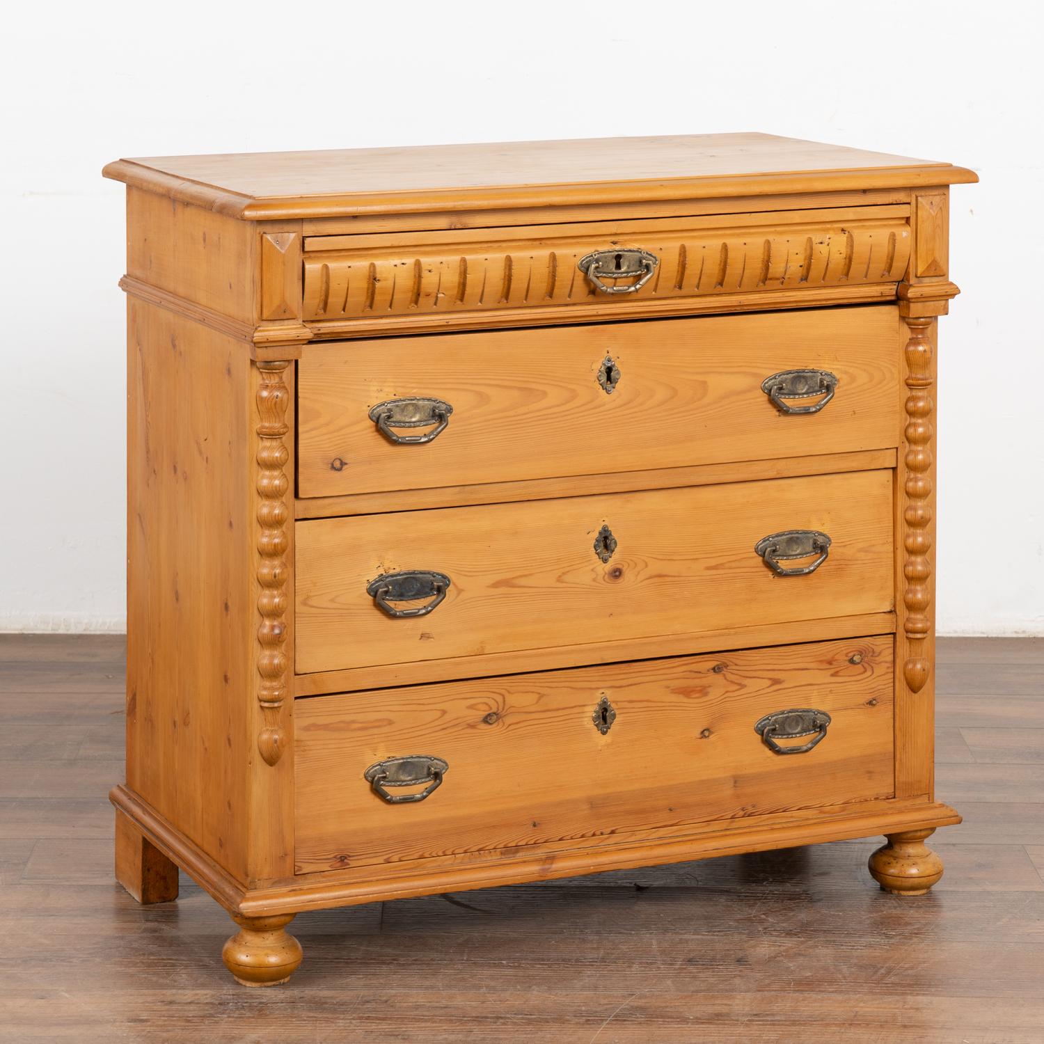 Antique pine chest of four drawers resting on bun feet.
Traditional half column detail, simple carved top drawer, dove-tail joints and brass pulls.
Note the natural wax finish that brings out the warmth of the pine. 
Restored, this nightstand is