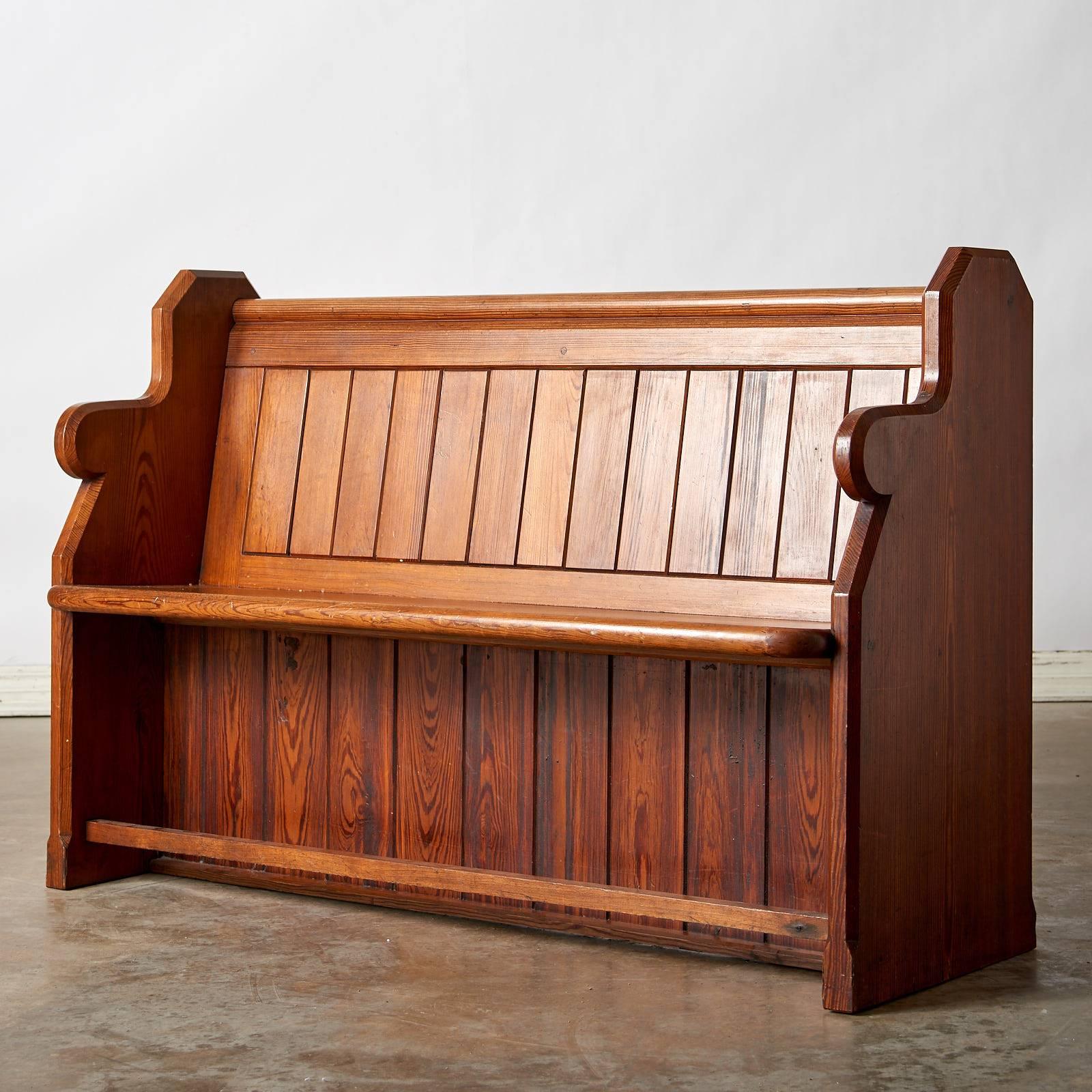 A standalone church pew of solid construction with bible holder behind backrest.