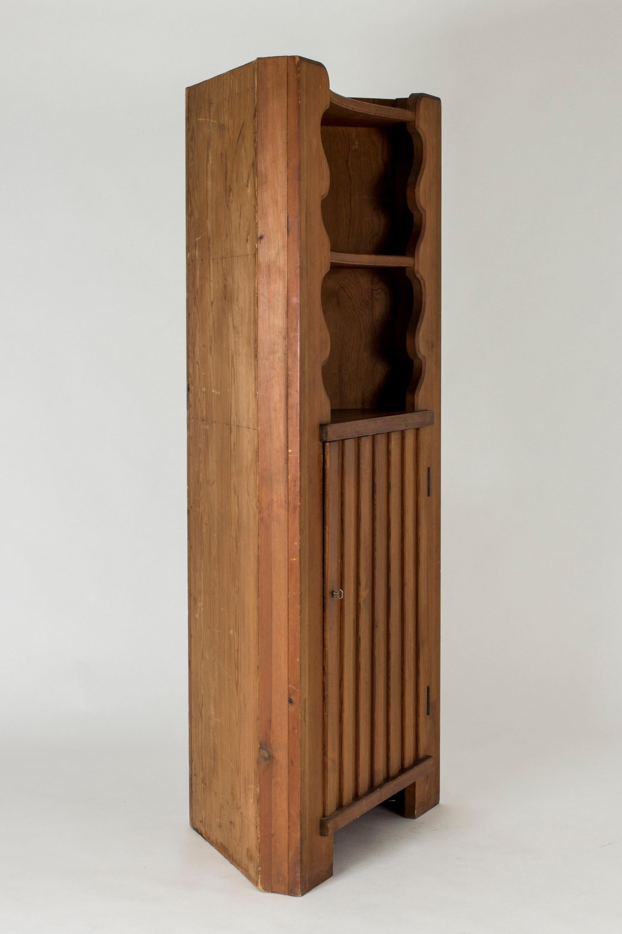 Pine corner cabinet, “Utö”, by Axel Einar Hjorth. Design included in NK’s line of “sports cabin” furniture. Carefully executed rustic expression, with beautiful wavy decor framing the top shelves.