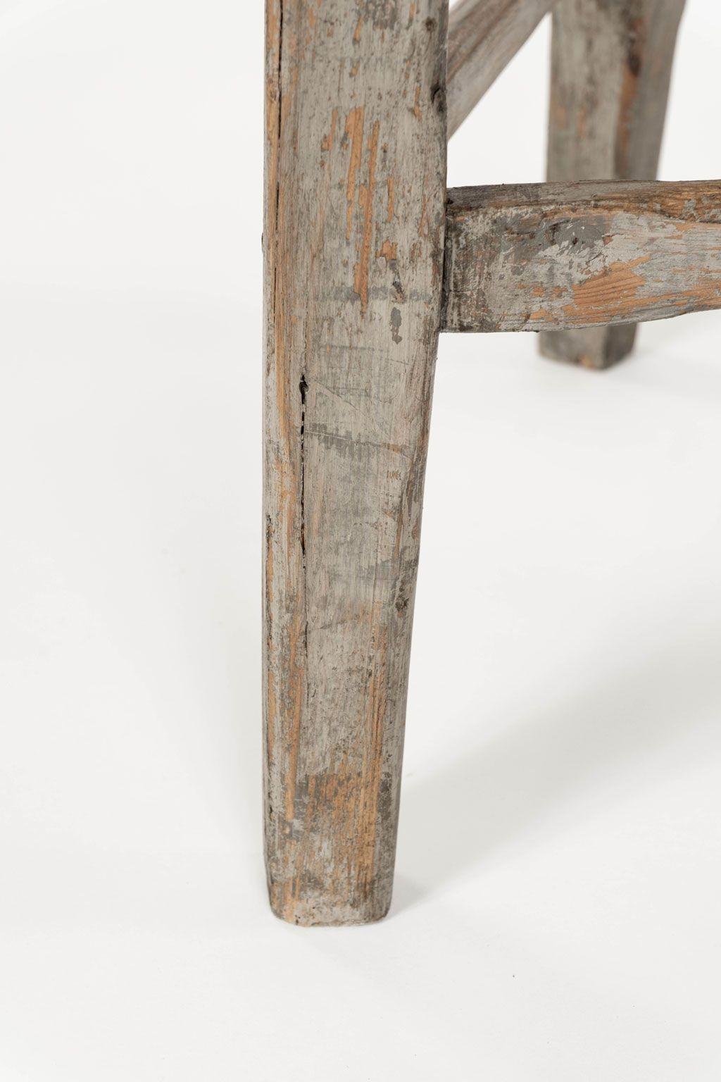 Pine cricket table upon gray painted base. Circular scrubbed pine top upon three chamfered legs. Remnants of gray and brown paint.