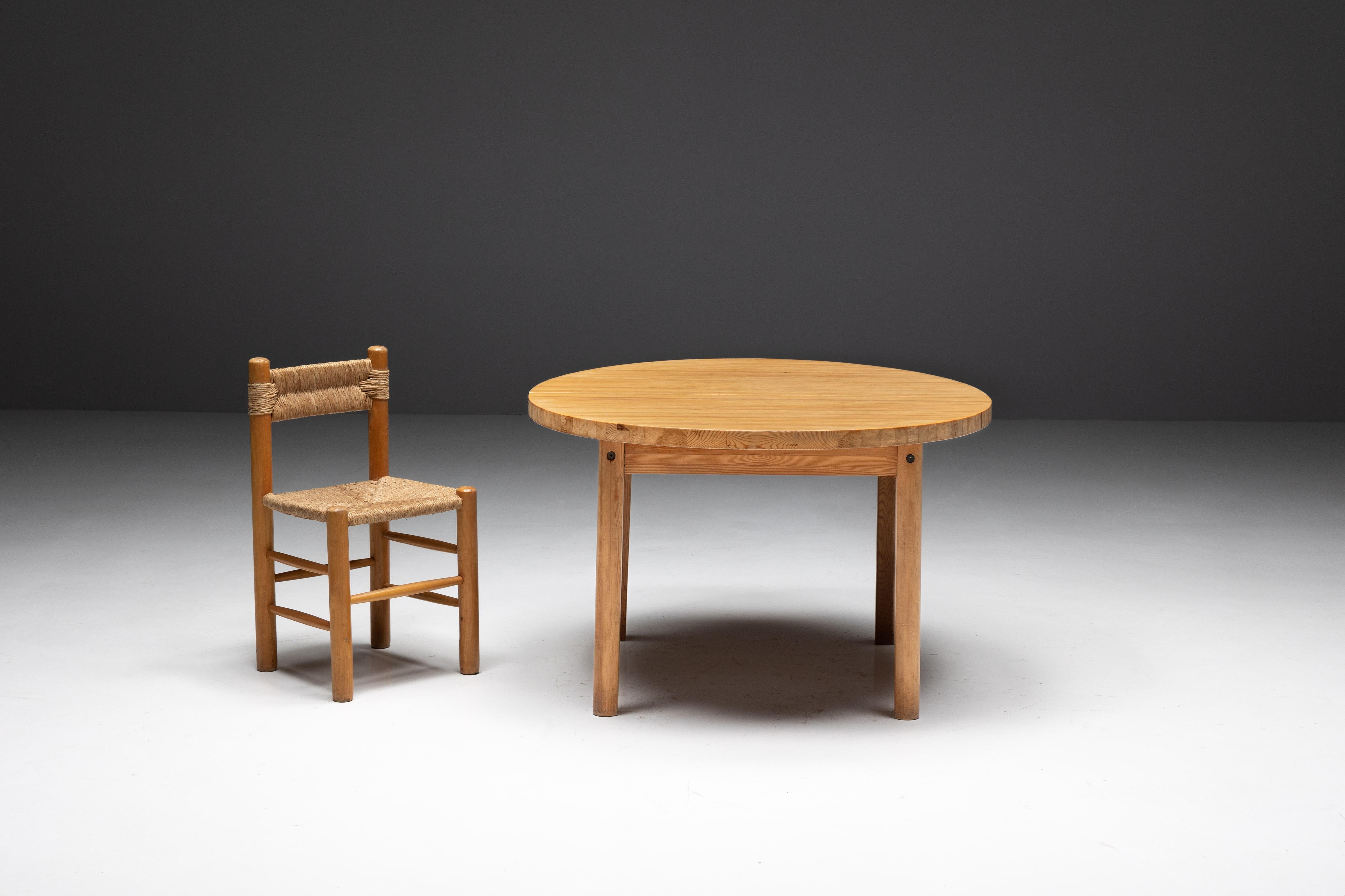 Table de salle à manger ronde en pin dans le style de Charlotte Perriand. Fabriquée en bois de pin, cette table présente un plateau enchanteur. Assortie sans effort à nos chaises de salle à manger en paille, comme le montrent les photos, cette table