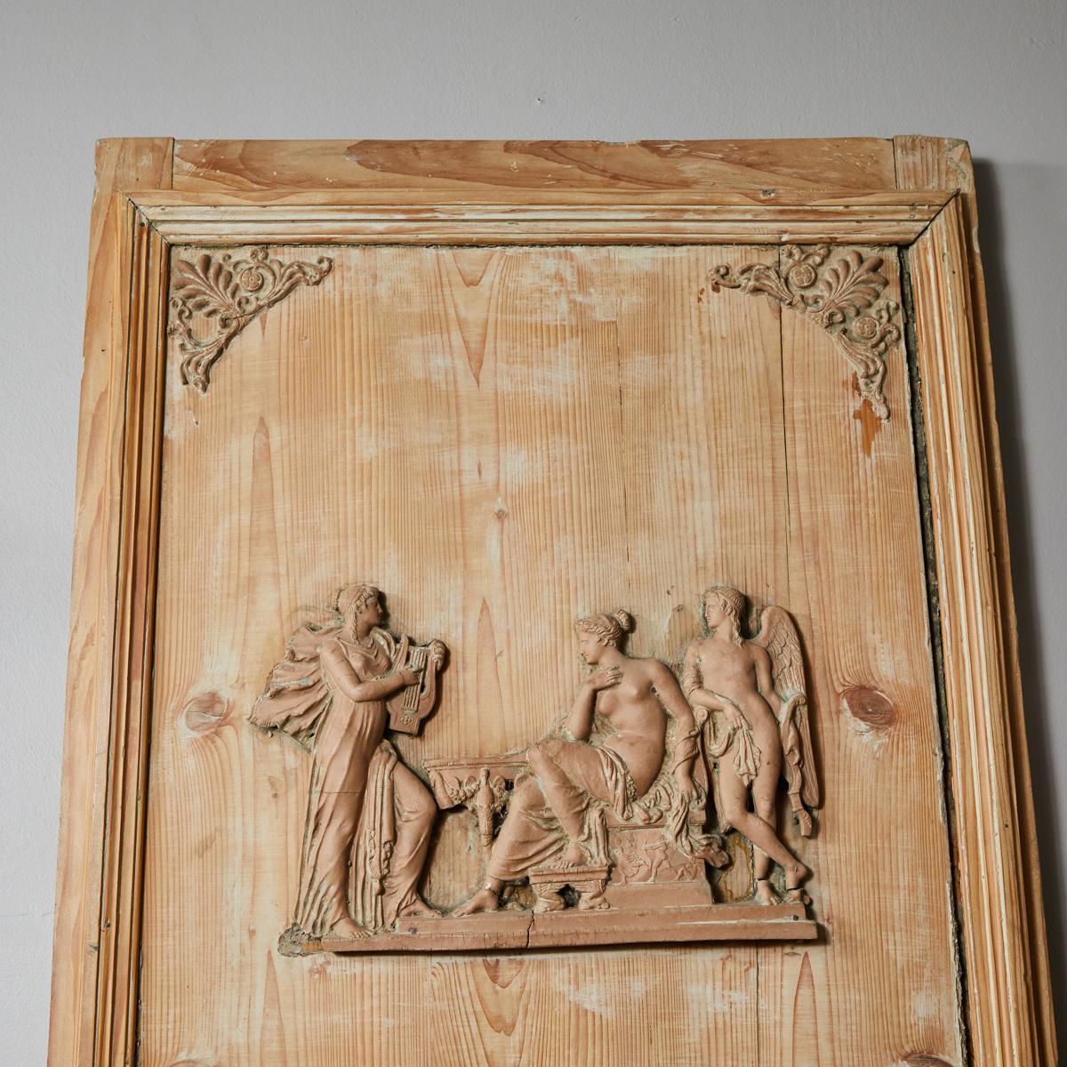 Pine Directoire trumeau from France circa 1820. The rectangular fluted frame encloses the trumeau top with scrolled foliate motif corners and a beautiful neoclassical frieze of a seated goddess flanked by a winged male figure and woman playing a