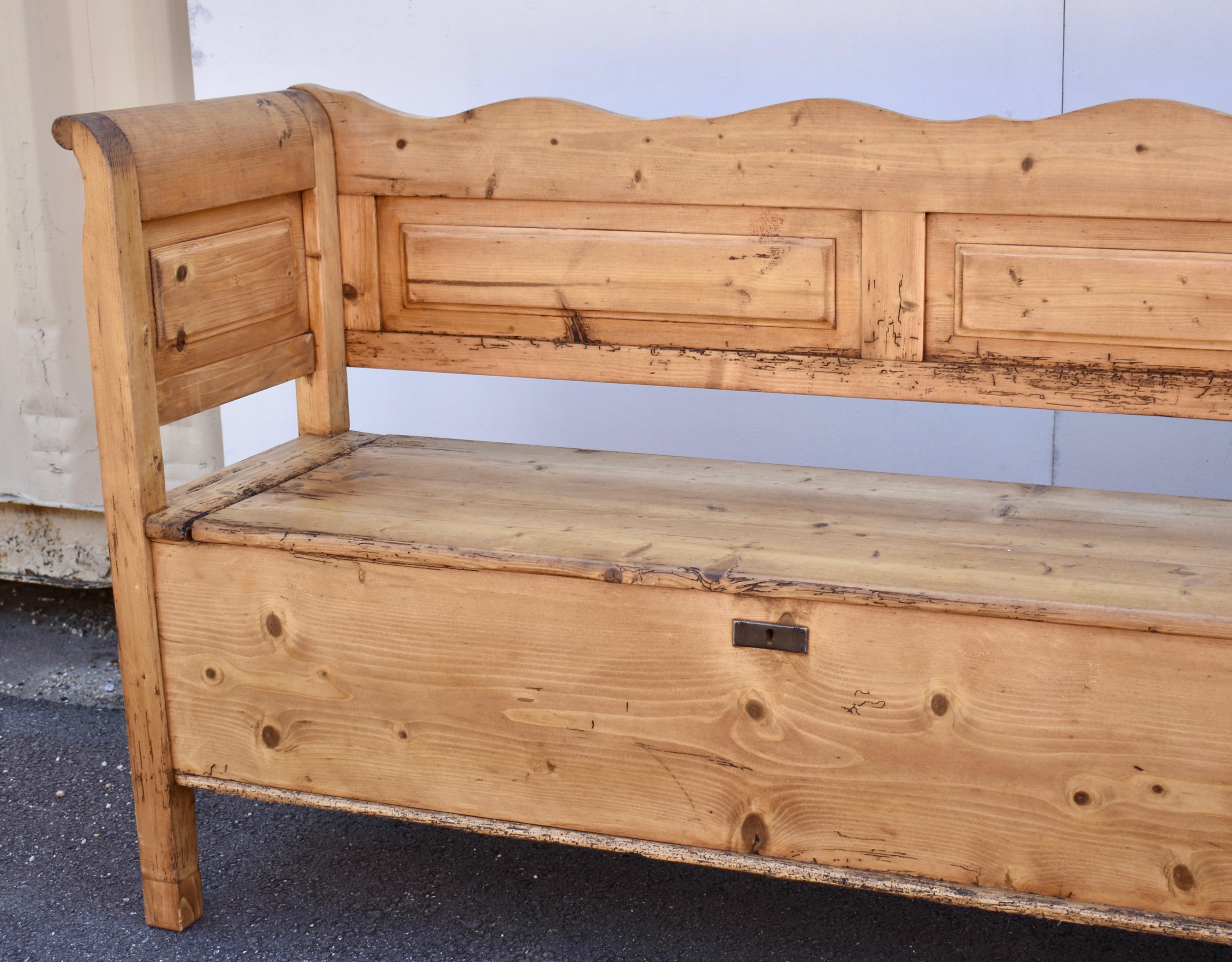 At almost ten feet long, this is quite the longest Hungarian box bench we have offered for sale.  Beneath a curvilinear top rail and a straight bottom rail are four raised panels.  The leg is straight and the integral arm is slightly scrolled,