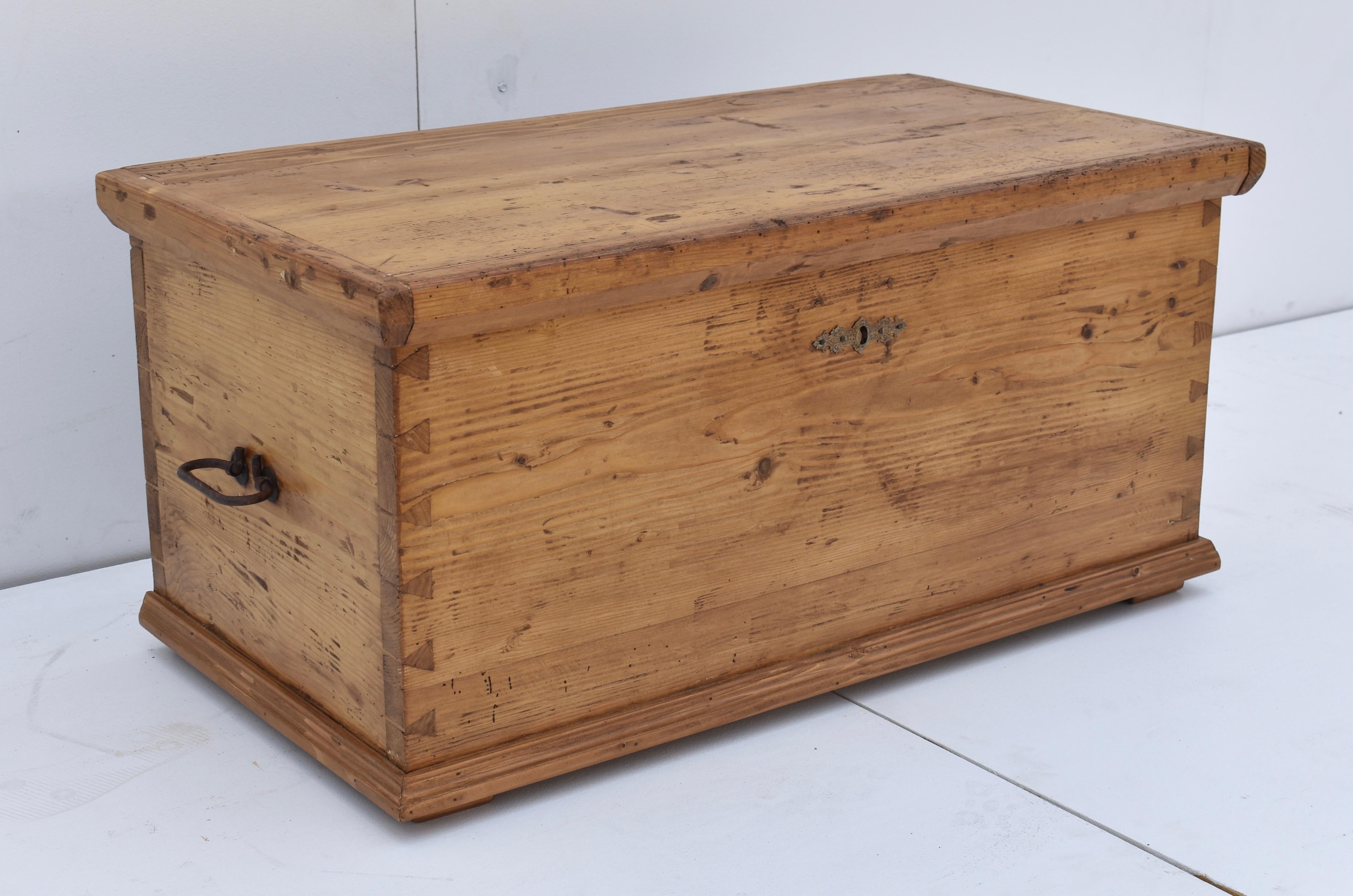 This is a plain and simple, but very pretty little hand-cut dovetailed blanket box, polished to a warm honey pine finish. The lid lifts on iron strap hinges to an open storage well. This is a great size for a use as a small coffee table or for