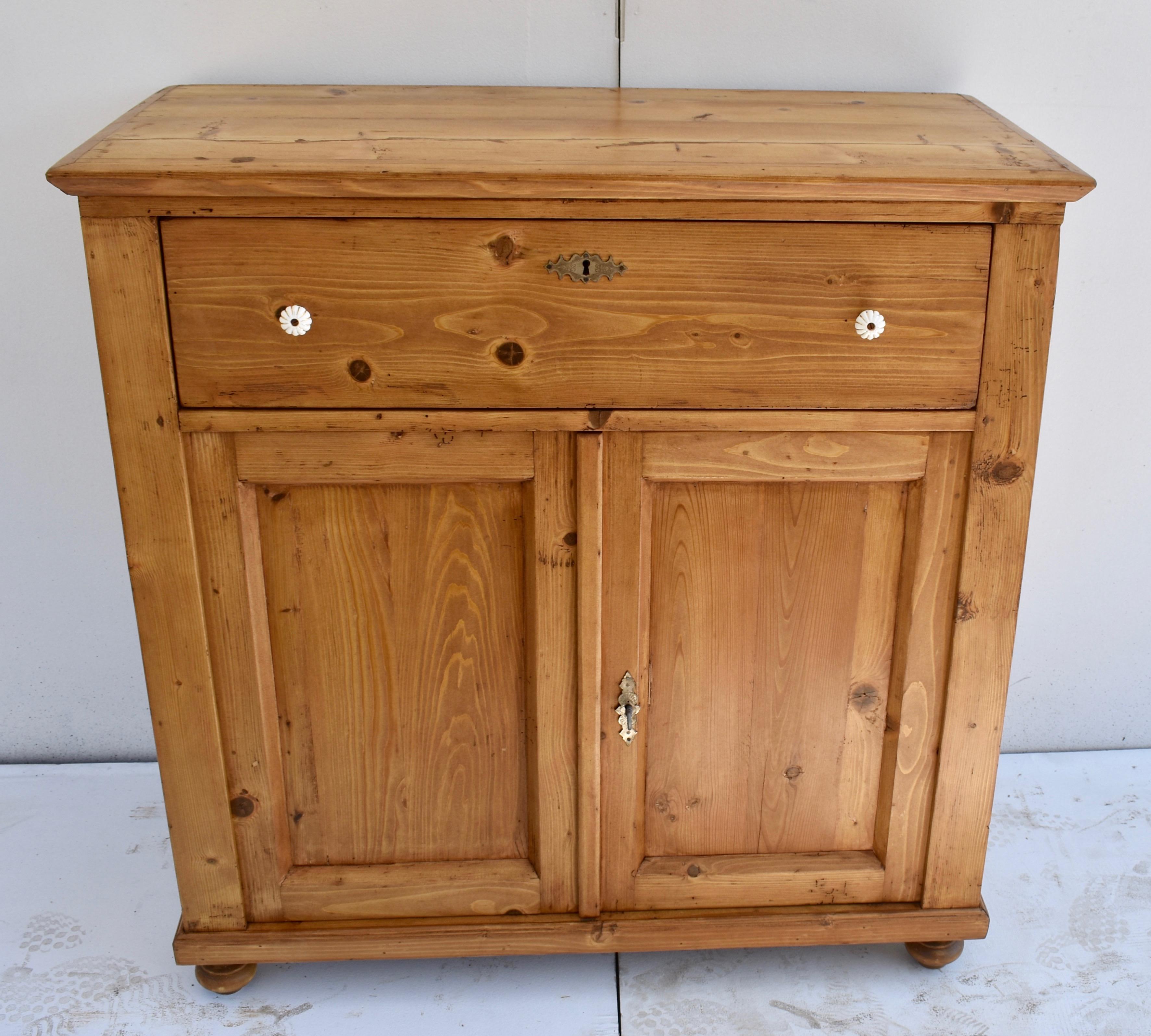 This plain and simple two door dresser base is built solidly using thick stock and its sturdy form has real country charm. The top is bordered with a crown molding and sits above a single deep drawer. Two doors with flat panels in chamfered frames