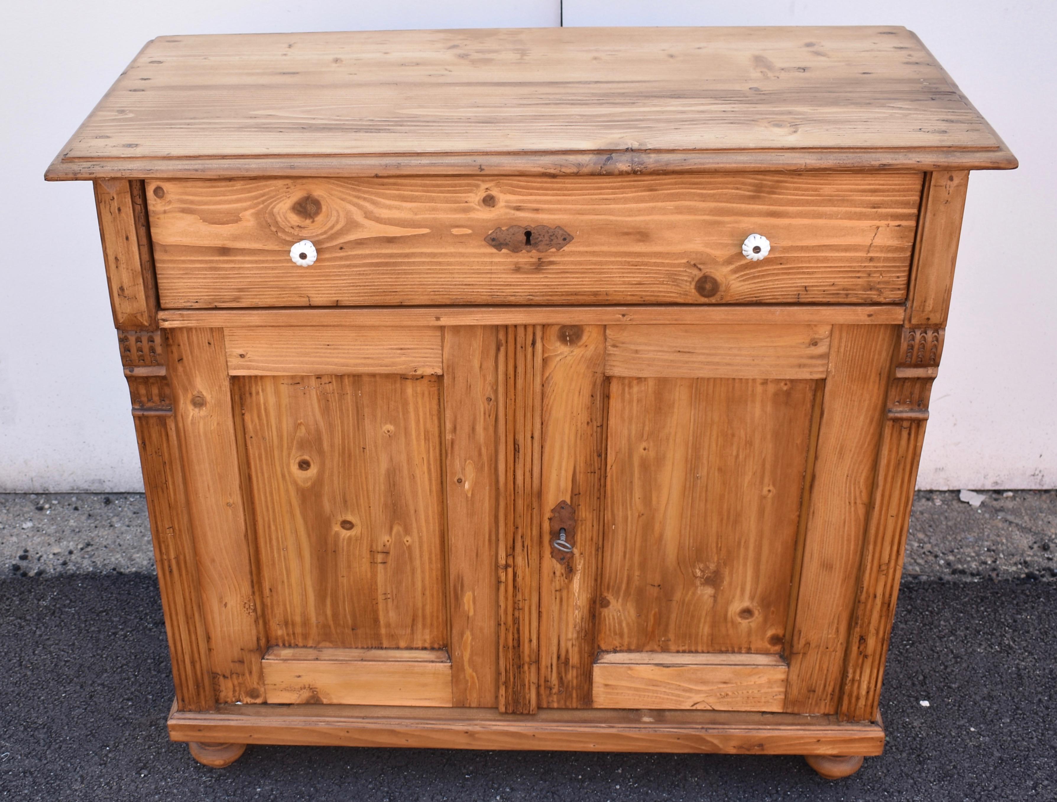 This sturdy and versatile dresser base has a step-down edge to the top, above a single long hand-cut dovetailed drawer. The two door frames have a nicely chamfered inside edge and enclose flat panels. The front corners have reeded molding and carved