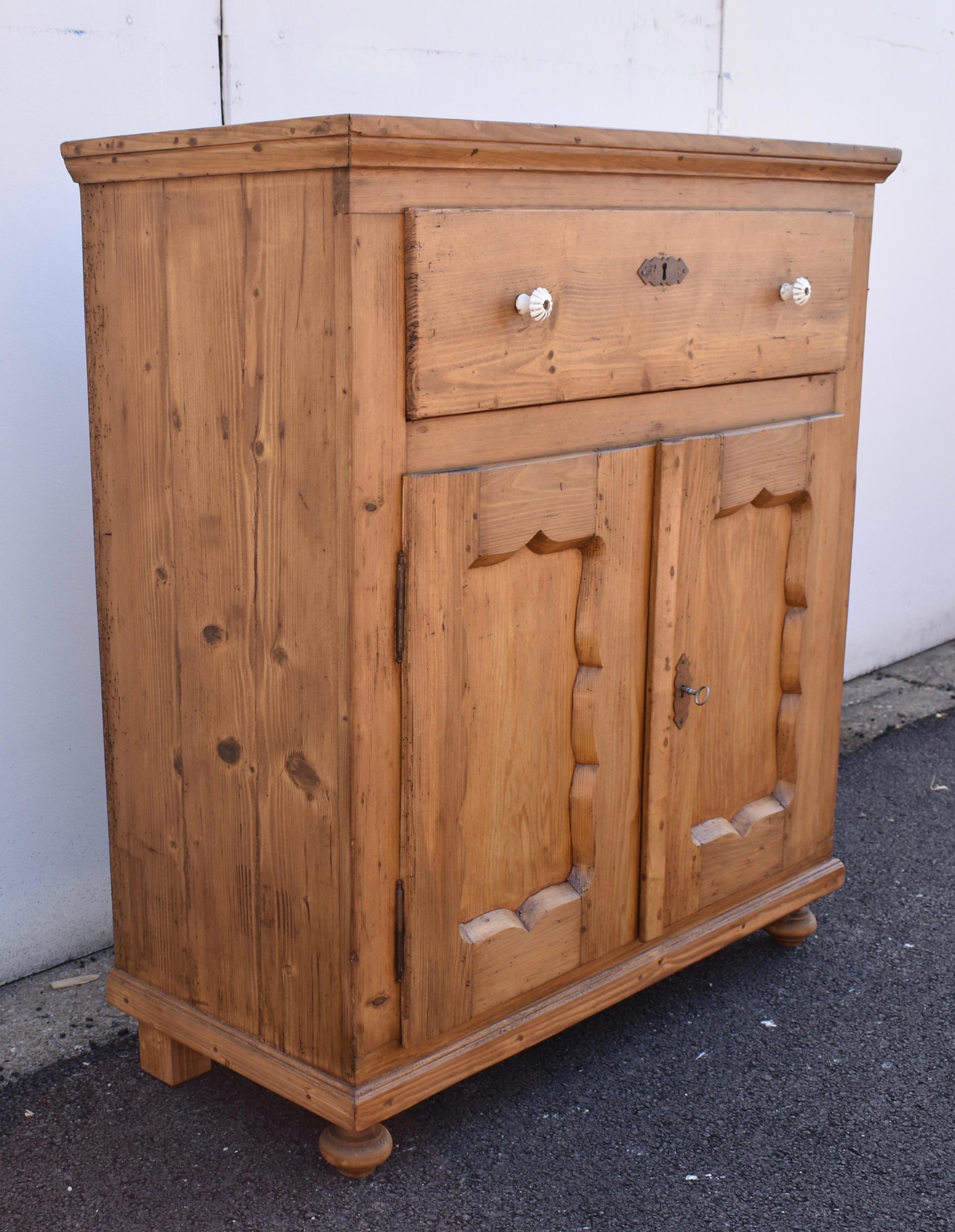This lovely little dresser base has exposed dovetails on the top with an ogee molding forming the crown.  The case is very plain as is the front of the deep single hand-cut dovetailed drawer.  The door frames have Dutch style scalloped rails and