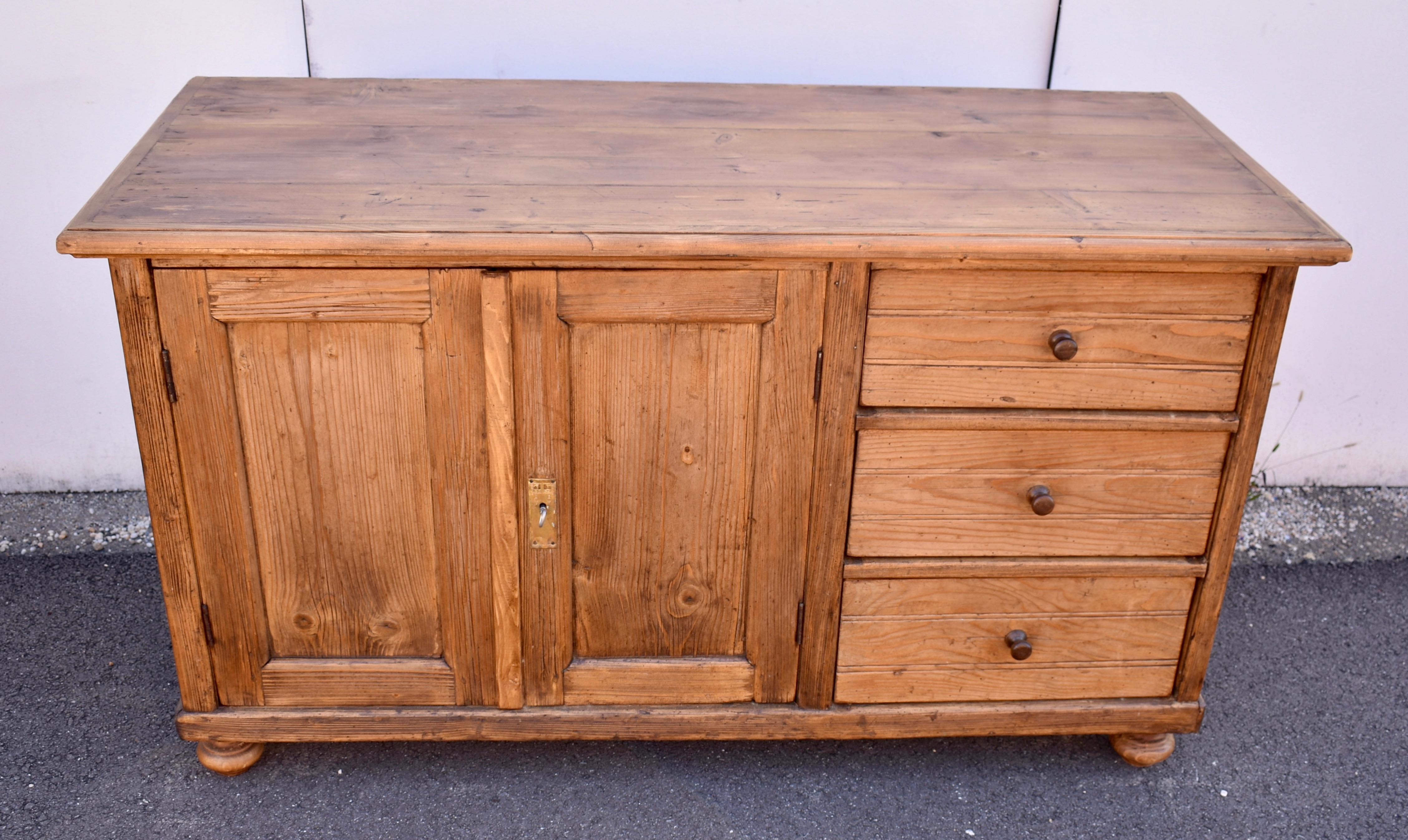 This is a fairly unusual configuration for a Central European dresser base, two flat-paneled doors on one side and three hand-cut dovetailed drawers on the other.  The top has a step-down edge formed with a trim of ogee crown molding.  The front is