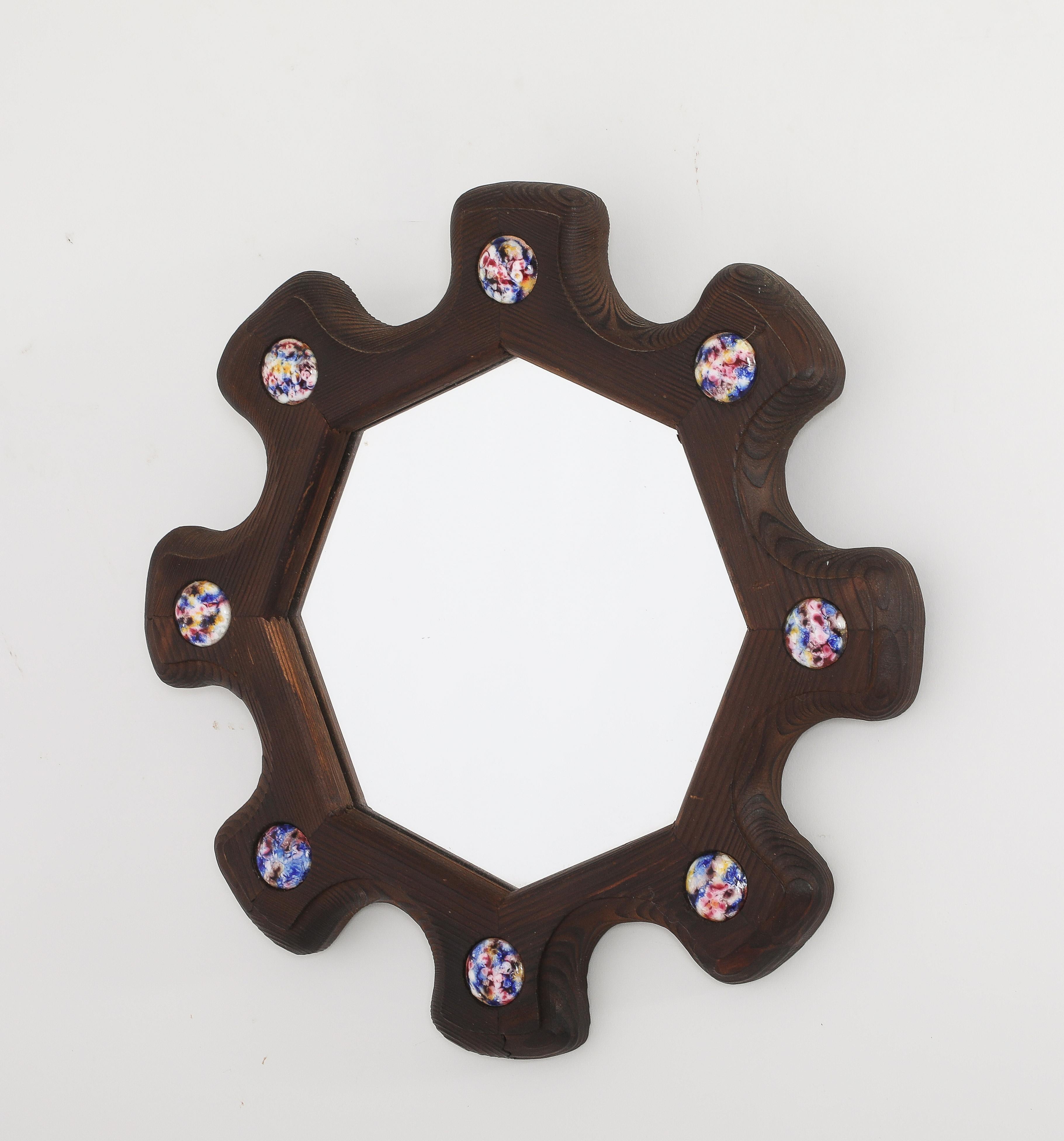 Specchio da parete intagliato a mano con un inserto interno ottagonale, il bordo intagliato come un ingranaggio e ornato da inserti astratti in rame smaltato.