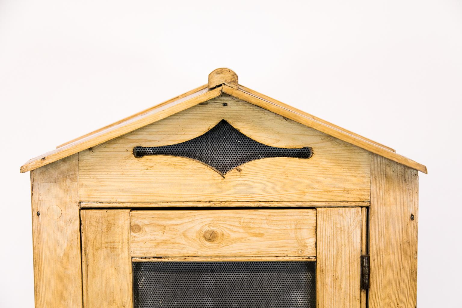 Pine English pie safe on legs has tin on three sides. There is a decorative screen, lined cut-out in the eave while the angled roof has an arched ridge CAP.
  
