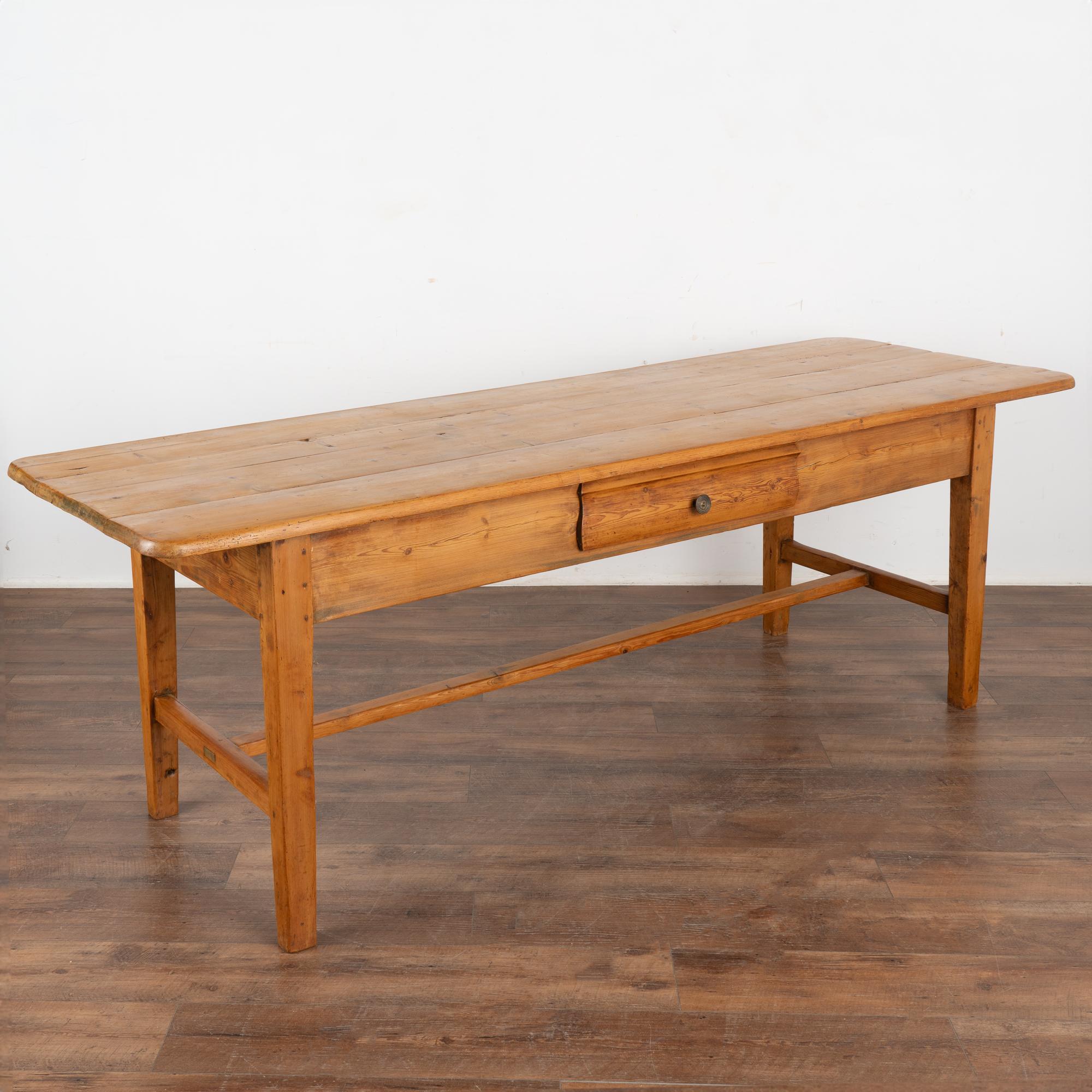 The beauty of this pine farm table comes from the warm aged pine and the clean tapered legs of the simple stretcher base.
It may have originally served as a kitchen work table in a country manor house; note the scratches, dings, stains and age