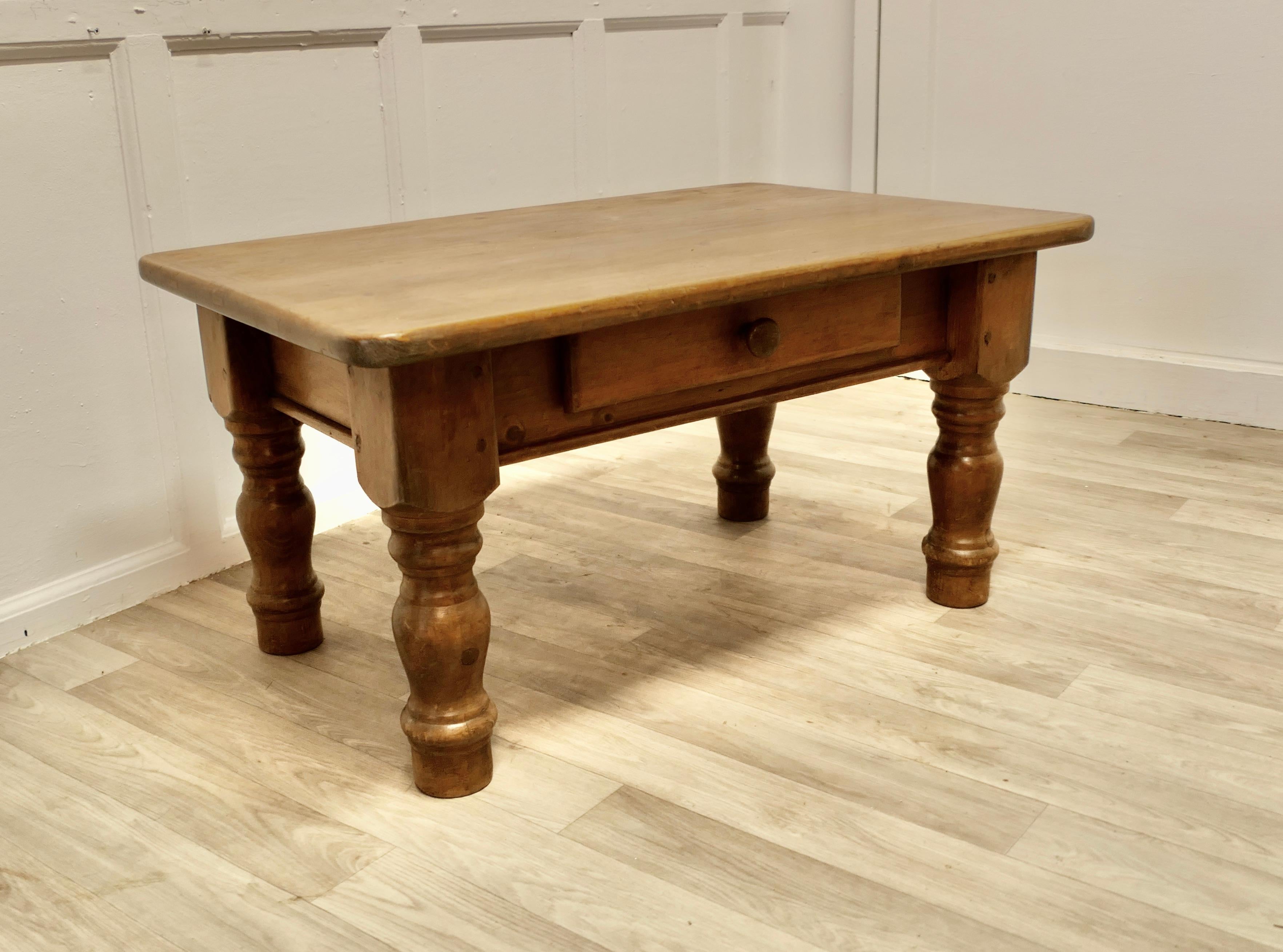 Table basse fermière en pin
  
Il s'agit d'une bonne table de ferme, dont les pieds ont été réduits en hauteur, ce qui en fait une table basse. 
Le plateau de la table est en pin d'un pouce d'épaisseur, les pieds sont tournés et il y a un tiroir.
Le