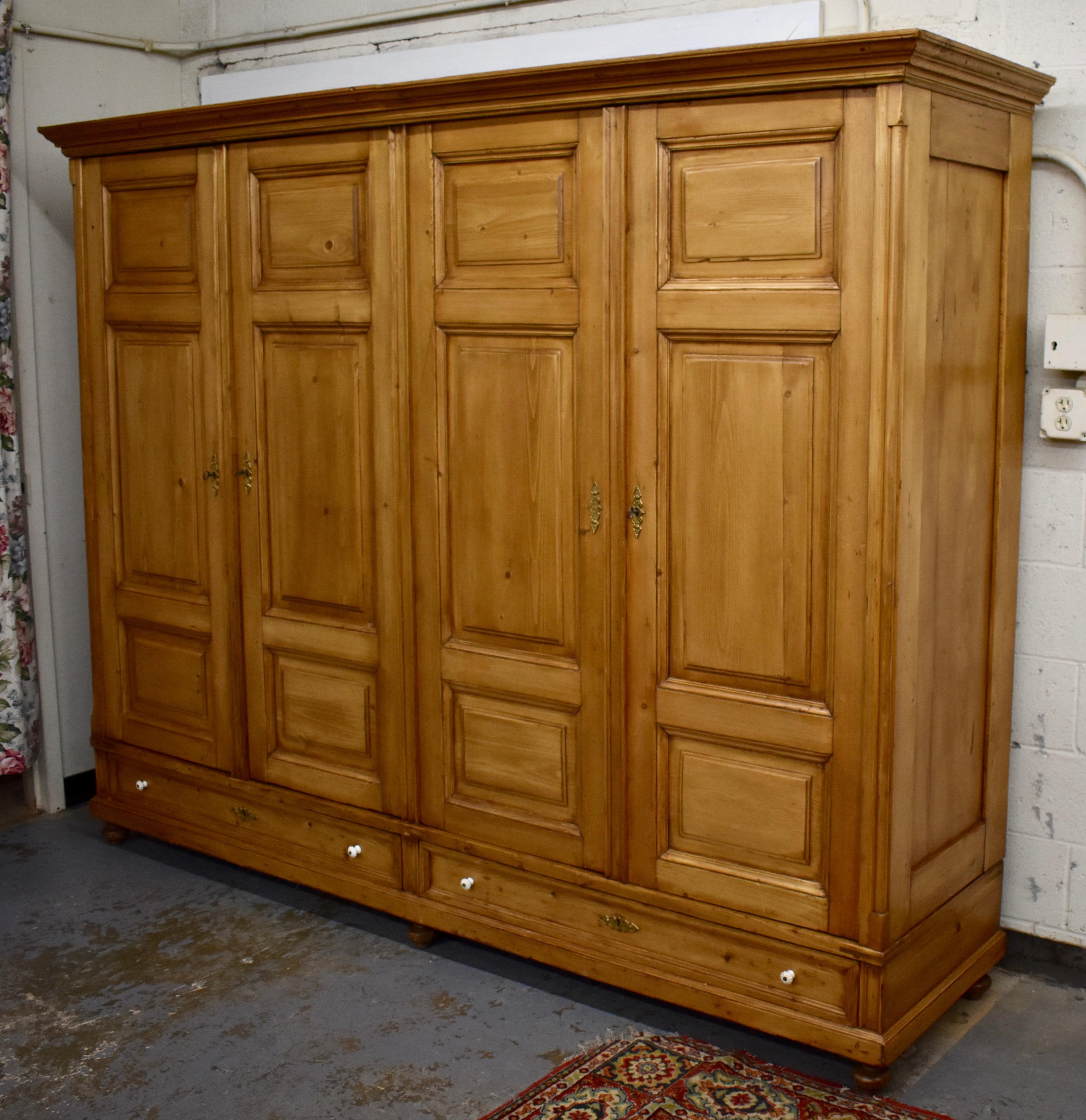 This is a rare find indeed. This handsome four-door armoire features a bold crown molding and a single flat panel to each side. The front corners are nicely chamfered and mounted with a plain half round column with a triangular base and capital.