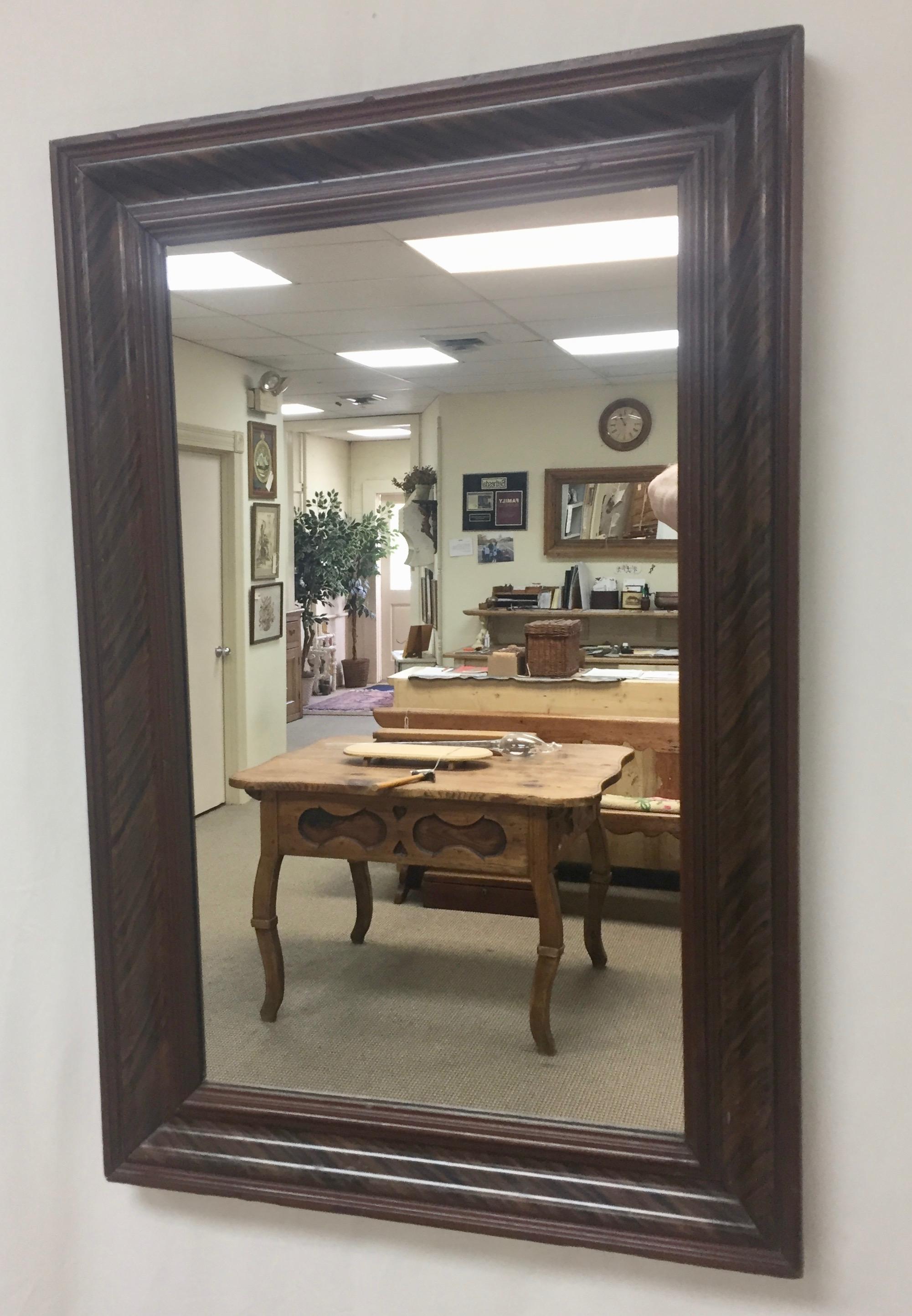 This pretty little wall mirror is made of pine, skillfully grain-painted in a stylized black walnut pattern. The painted lines of black, alternating with shades of brown, flow diagonally across the smooth ogee curves of the pine frame. The frame and