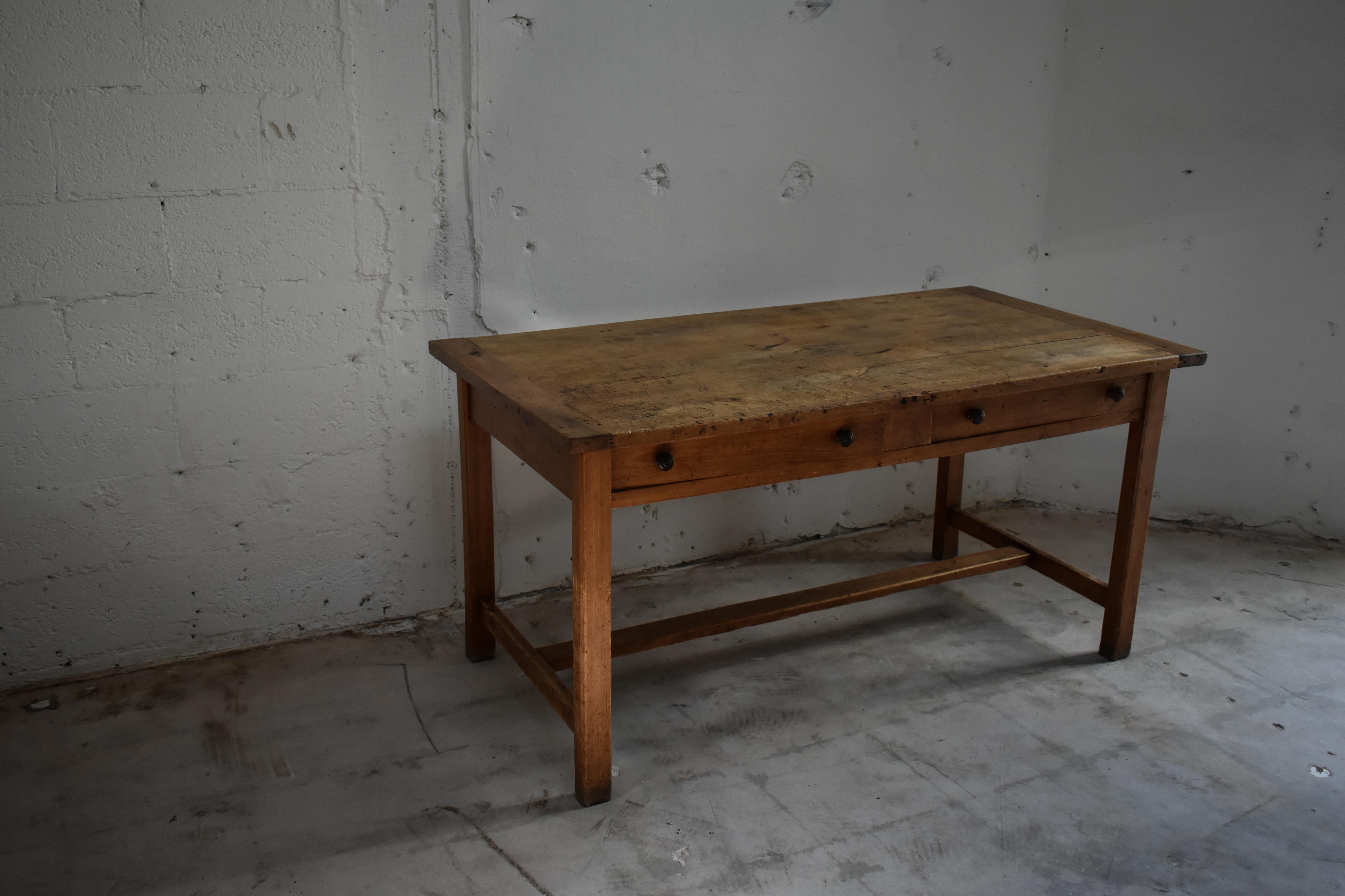 A rustic antique pine work table, showing the honest wear and patina of decades of daily use. The rectangular top bears a beautifully worn surface with marks and tonal variations that speak to its history. Supported by square legs joined by simple