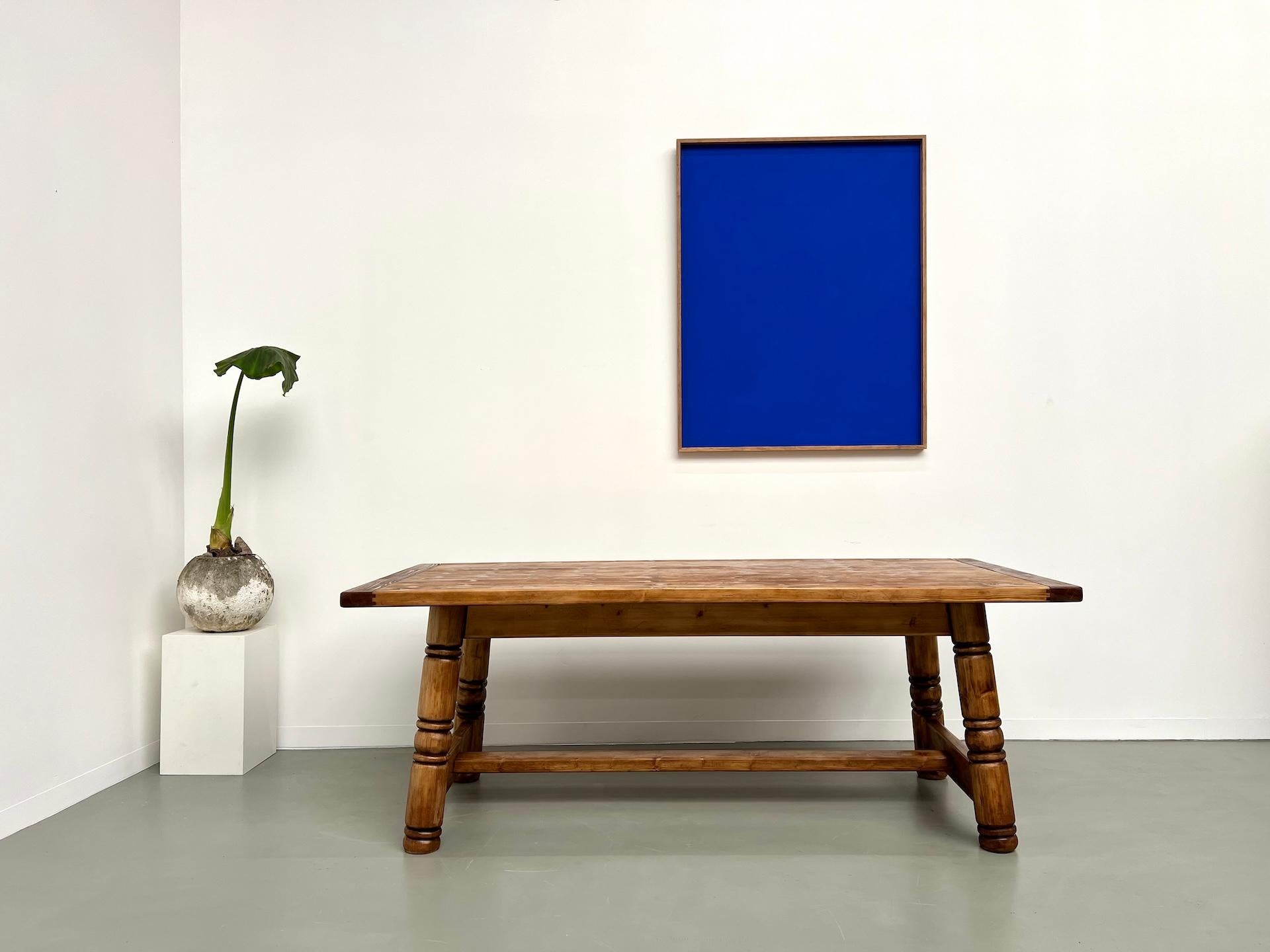 This beautiful modernist solid pine dining table dates back to the 1970s. It boasts a unique look with its distinctive base, similar to the work of designer Georges Robert. Fully restored and finished with a satin varnish, this impeccable table will