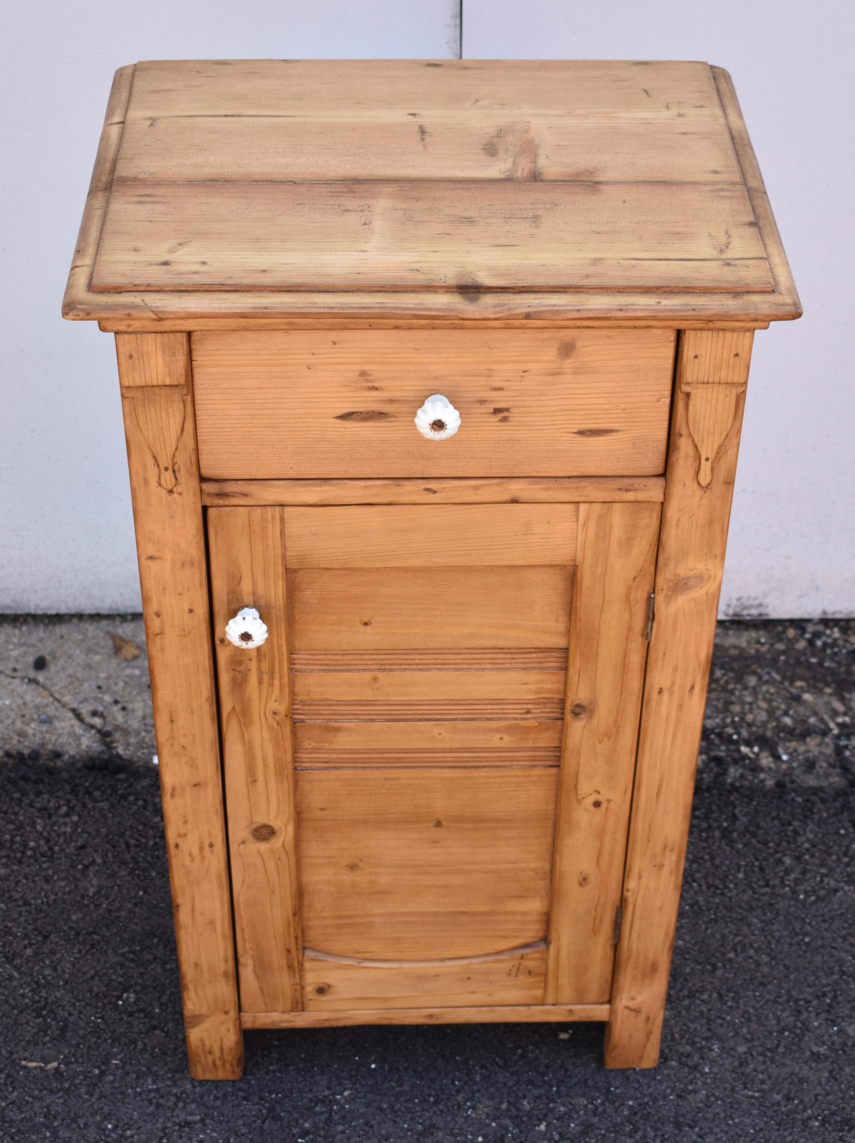 Larger than most, this pine nightstand is an unusual variation on a common theme. The top has a step-down routed edge with concave molding beneath, to form a crown. The sides are paneled with the stiles running top to floor to form the feet. A