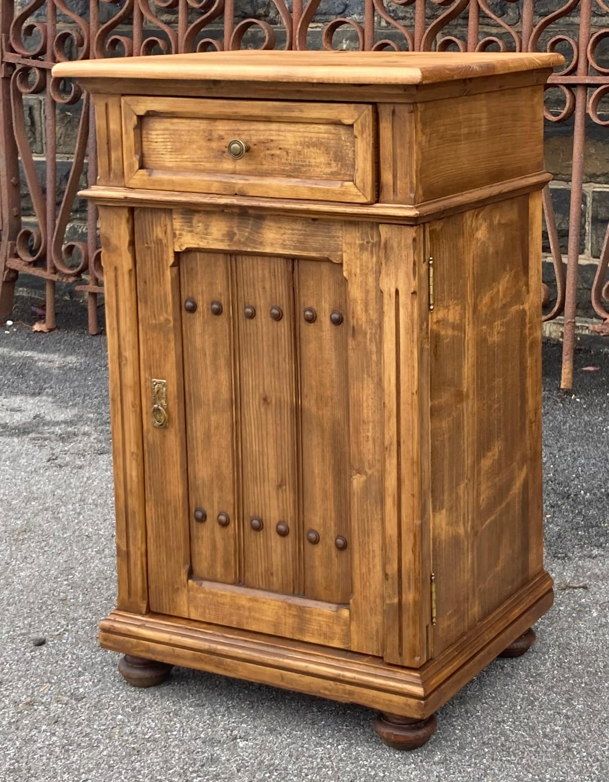 Avec l'audacieuse moulure chanfreinée autour de la façade du tiroir,  qui se répète dans l'encadrement de la porte, avec les deux cannelures verticales incisées dans le panneau de la porte et les deux rangées de six boutons en bois dur, suggérant