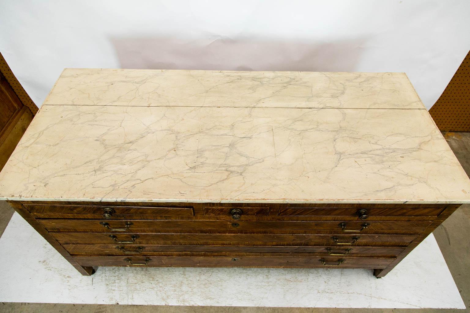 The top of this English portfolio chest is faux painted to simulate white marble with gray and tan veining. It has a one inch shrinkage separation in the top and an apparent square repair in the middle that was done before the faux painting. The