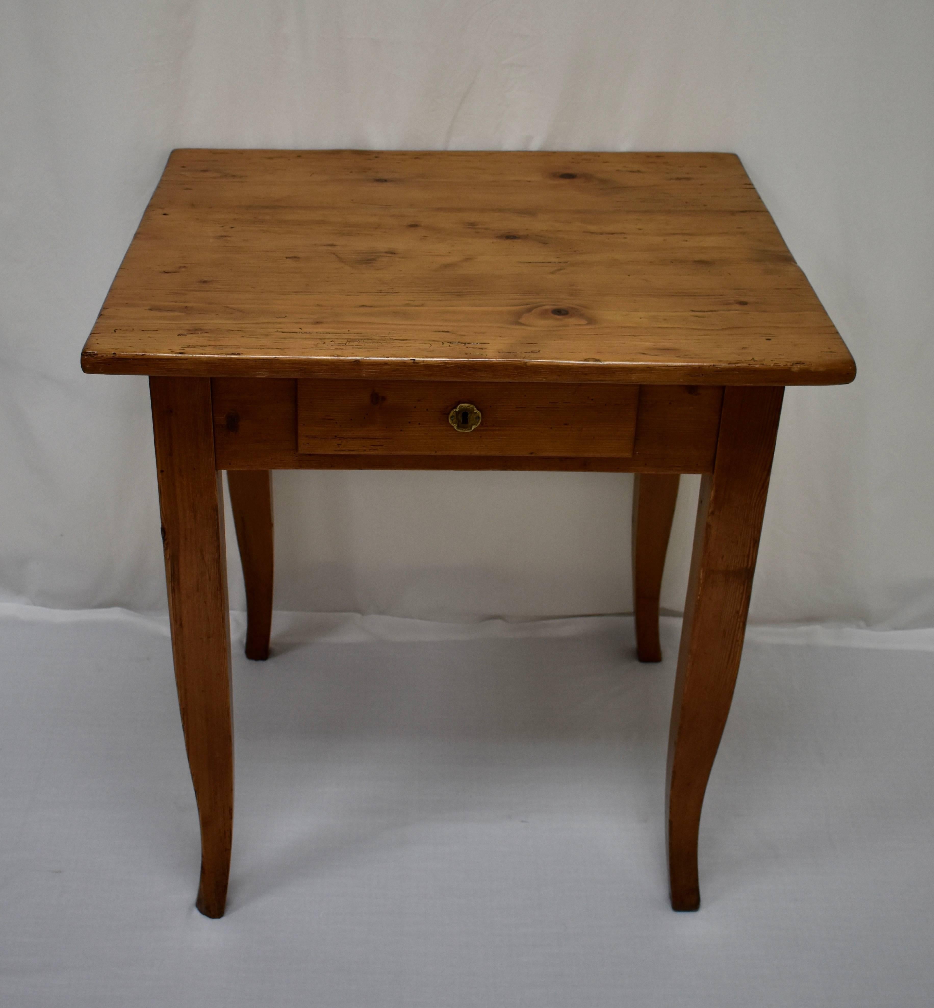 This lovely little writing table has a 1” thick three board top which has been beautifully naturally distressed over decades of purposeful use. The base features an overlay pencil drawer, with an interior depth of 18”, and a pretty pressed brass