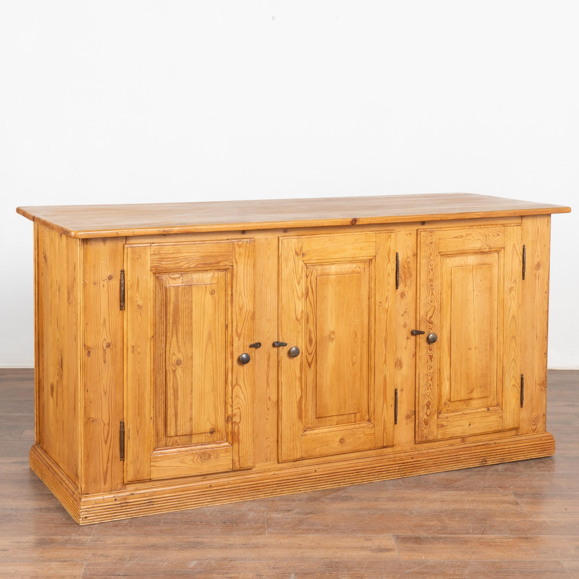 This antique pine shop counter has 3 cabinet doors revealing interior with one interior shelf. 
This country sideboard could be used as a buffet or a kitchen island with it's ample storage and beautiful paneled back which makes it free standing.
The