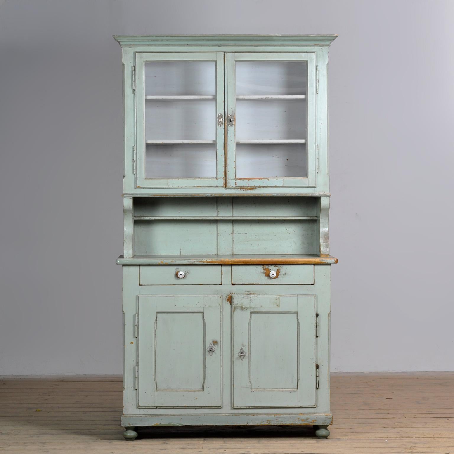 Grande credenza in legno con vernice originale, realizzata intorno al 1900. La credenza è composta da due parti. La parte superiore presenta due ante con due ripiani. La parte inferiore è dotata di due cassetti e due ante con un ripiano per un ampio