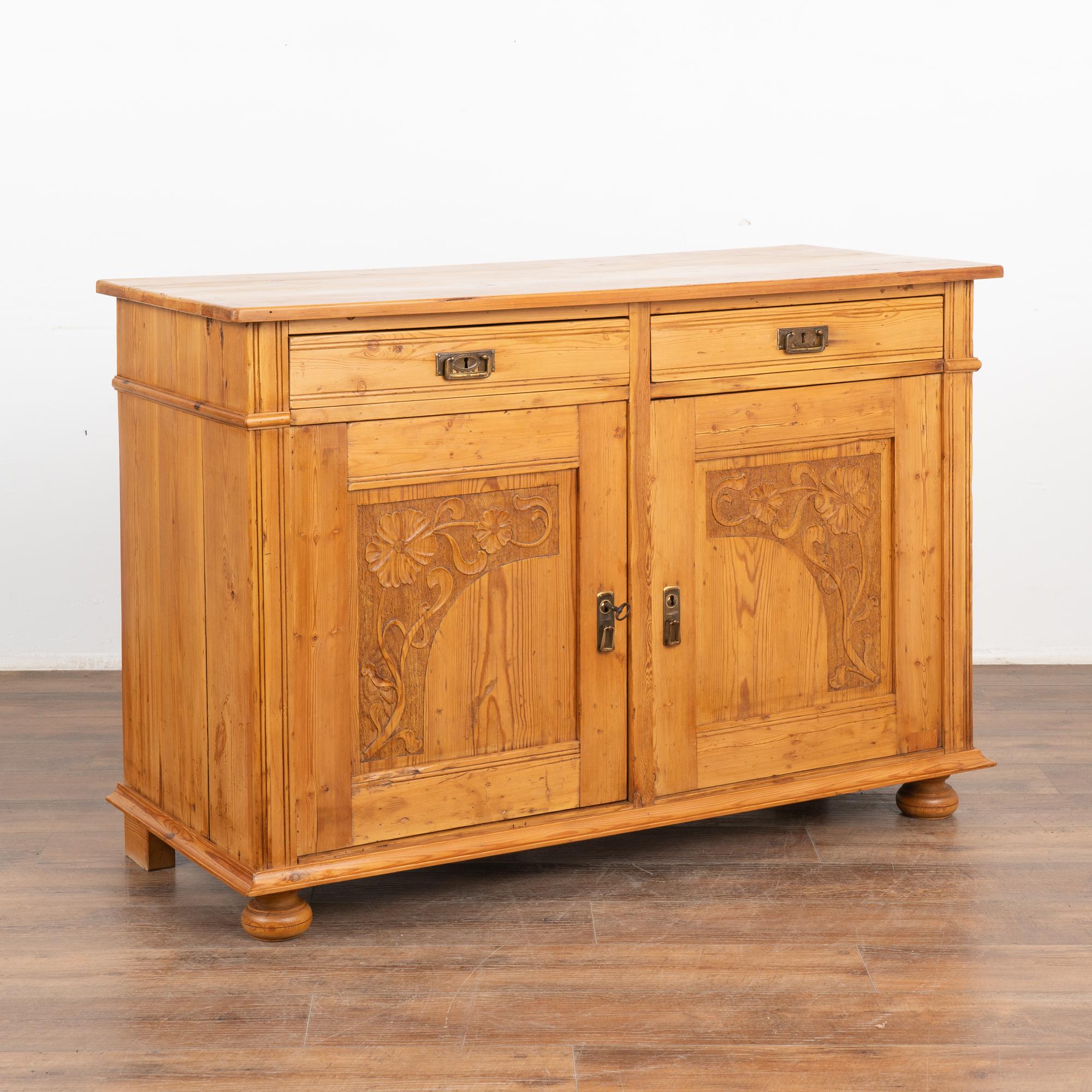 Danish pine sideboard with lovely art nouveau style floral carving along front door panels.
Restored and waxed, this cabinet has a great interior divided shelving for storage and organization.
Solid, strong and ready for use. One key included; old
