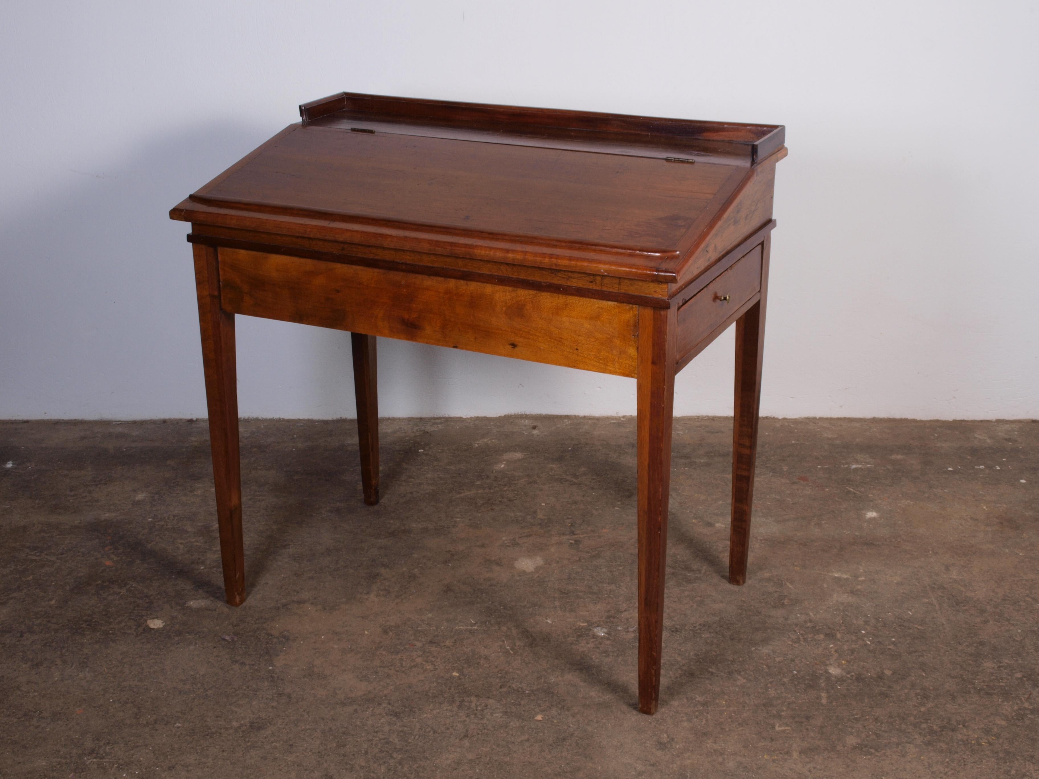 Antique Danish slant top desk, circa 1890s. Made for a rural schoolmaster, this pine desk retains its original character with minor mars and stains, protected by a smooth finish. Features ample storage compartments under the top. Danish design,