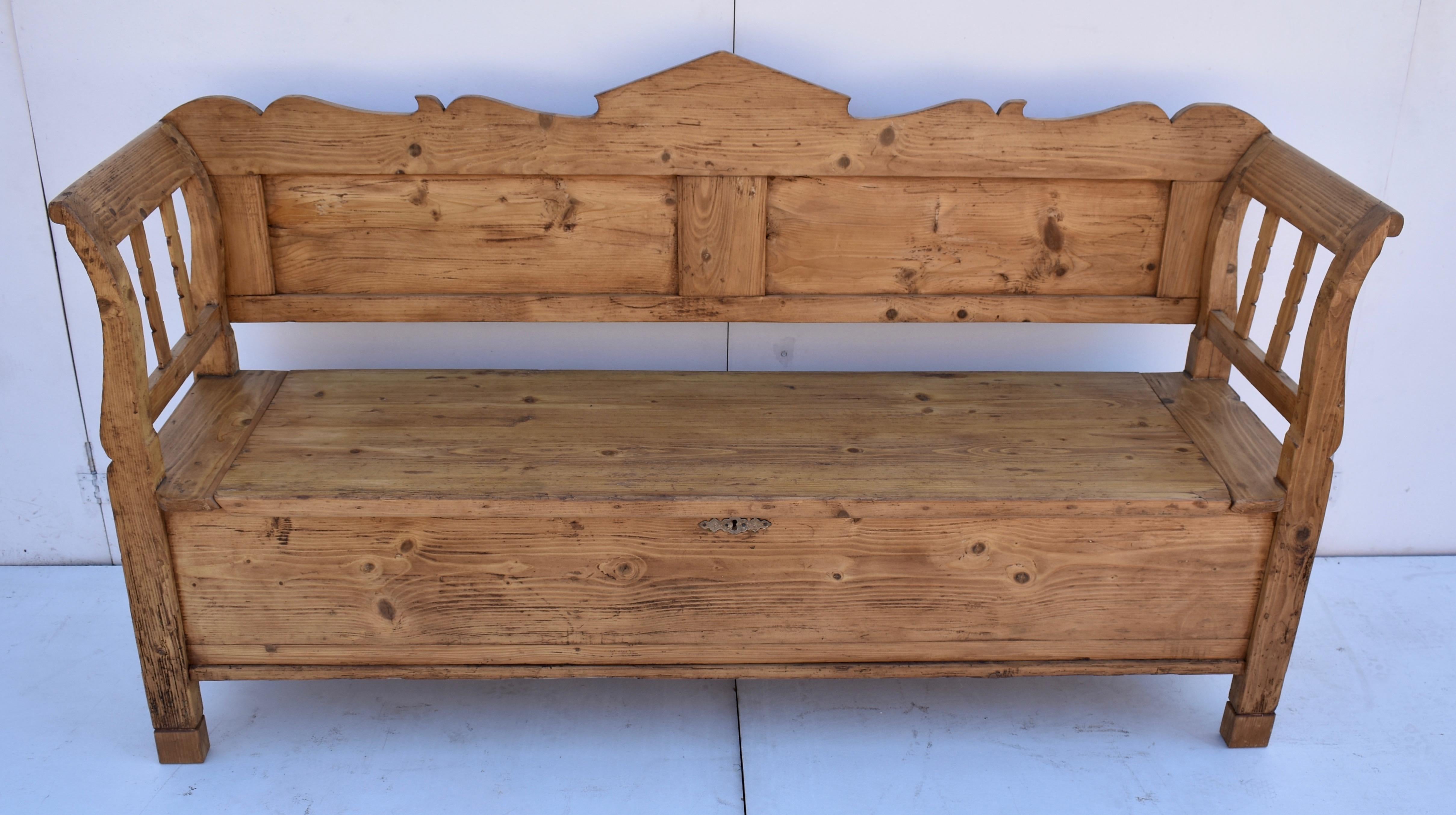 This handsome pine Storage Bench features a scalloped top rail above two flat panels. The scrolled arms enclose two notched splats on each side. The seat, braced with cross members on the underside, lifts to reveal a deep storage well,