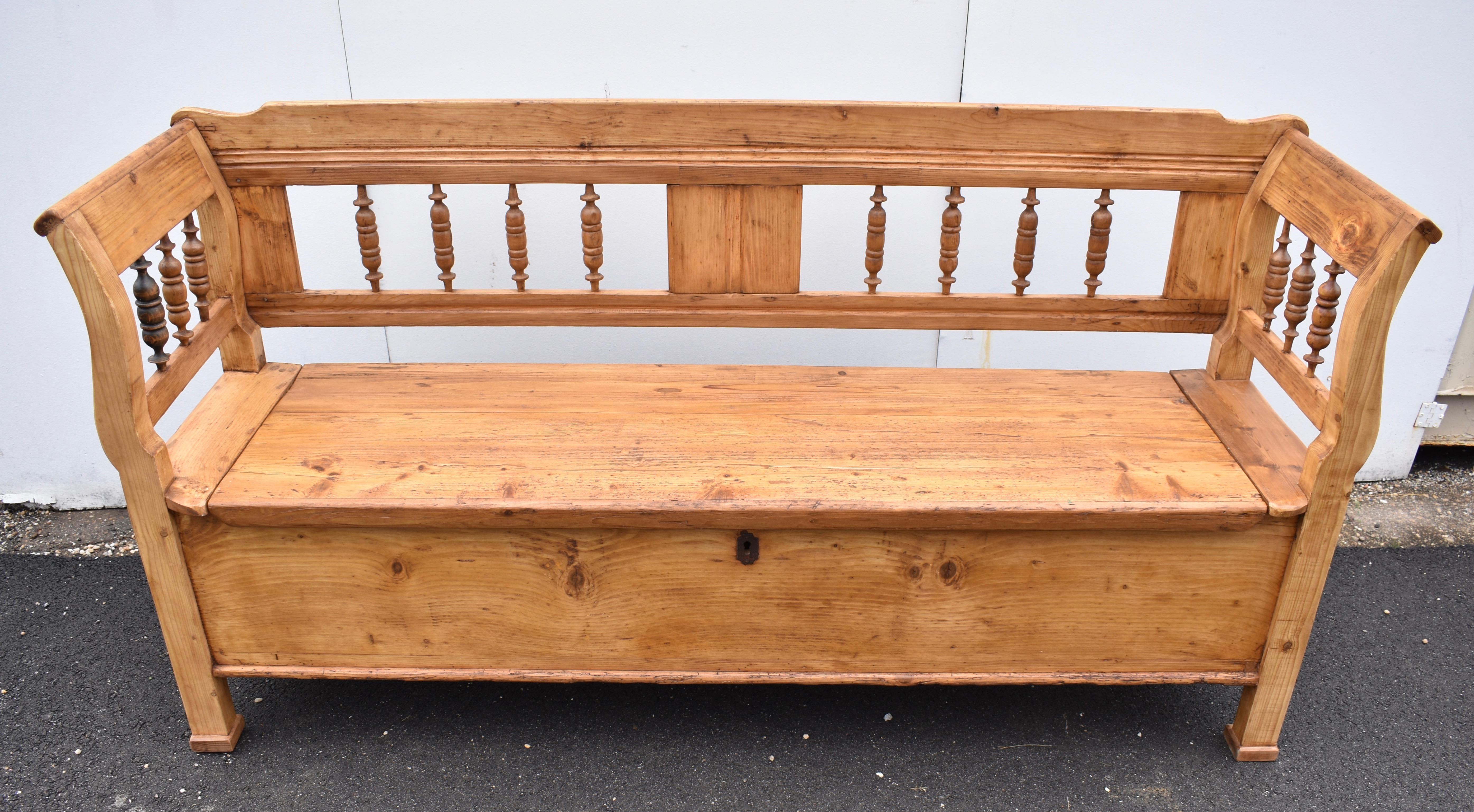 What a beauty! This outstanding pine box bench has fluted grooves running the length of the top and bottom back rails.  A broad central stile with reeded decoration creates two “windows”, each framing four turned hardwood full balusters. The legs