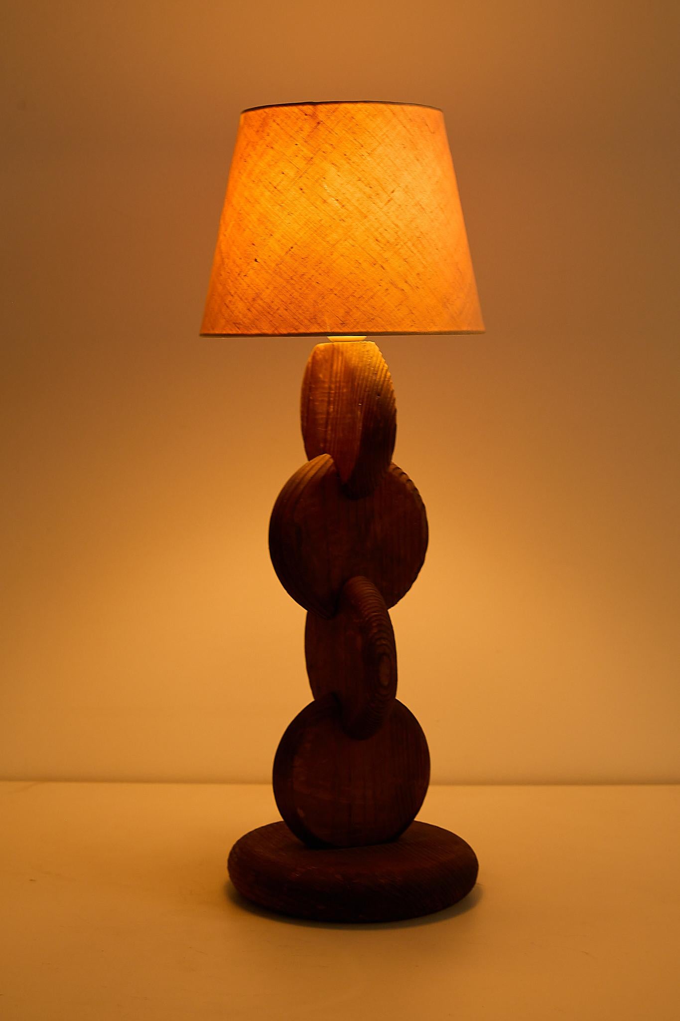 Temde table lamp, Switzerland, 1970s. Sculptural stacked-wood base with the original fabric shade; the shade shows some small tears to the inner lining but remains structurally sound.