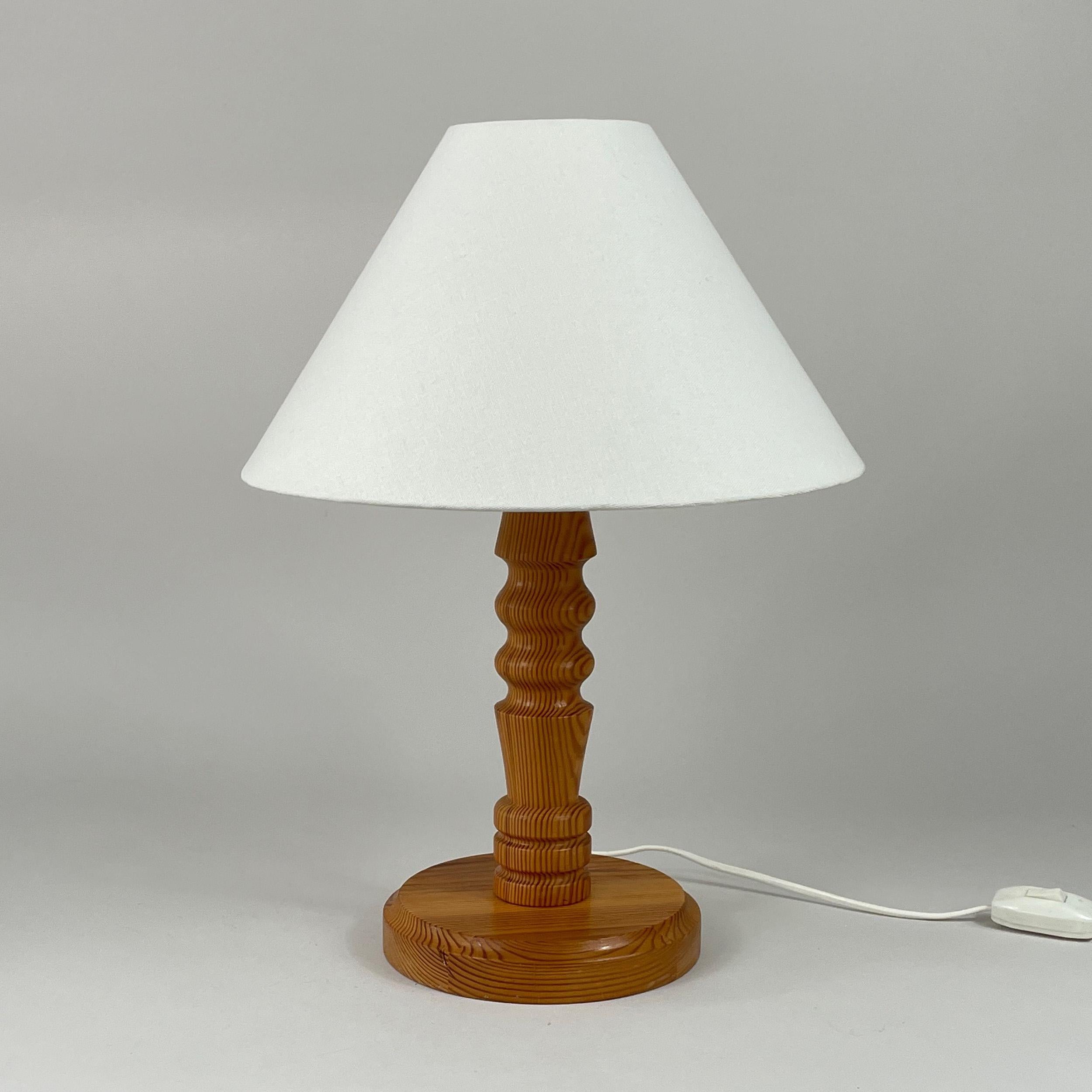 Lampe à poser en pin, design suédois, années 1970

Cette lampe de table présente une base en bois tourné avec des rainures et des courbes complexes, caractéristiques de l'artisanat scandinave de l'époque. Le bois de pin naturel présente une finition