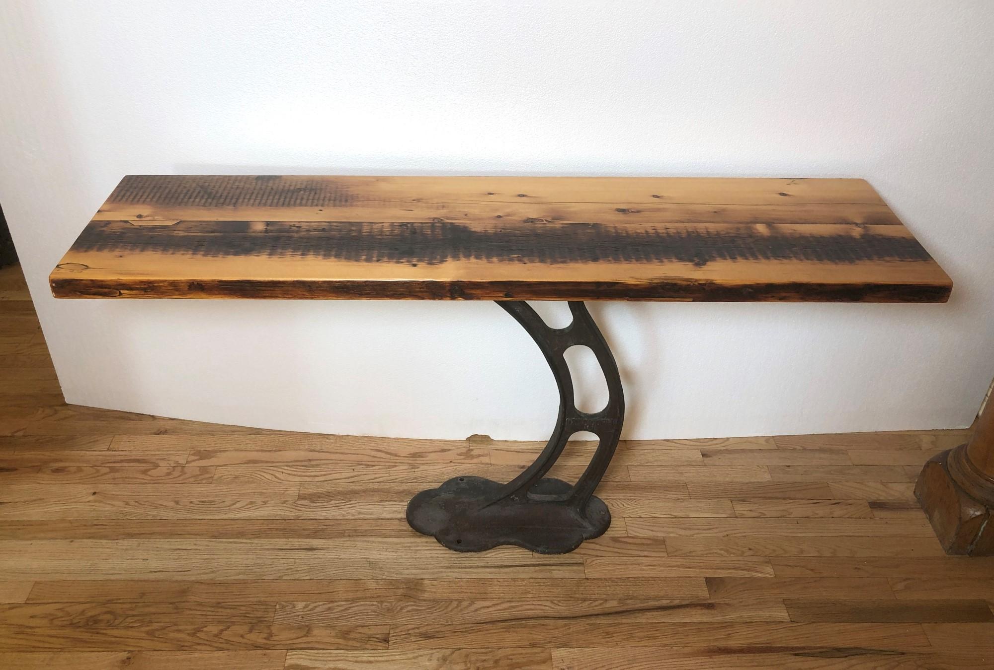 Pine table top made from reclaimed floor joists mounted to an early 20th Century curvy black cast iron industrial base. Cast iron base manufactured by and embossed 