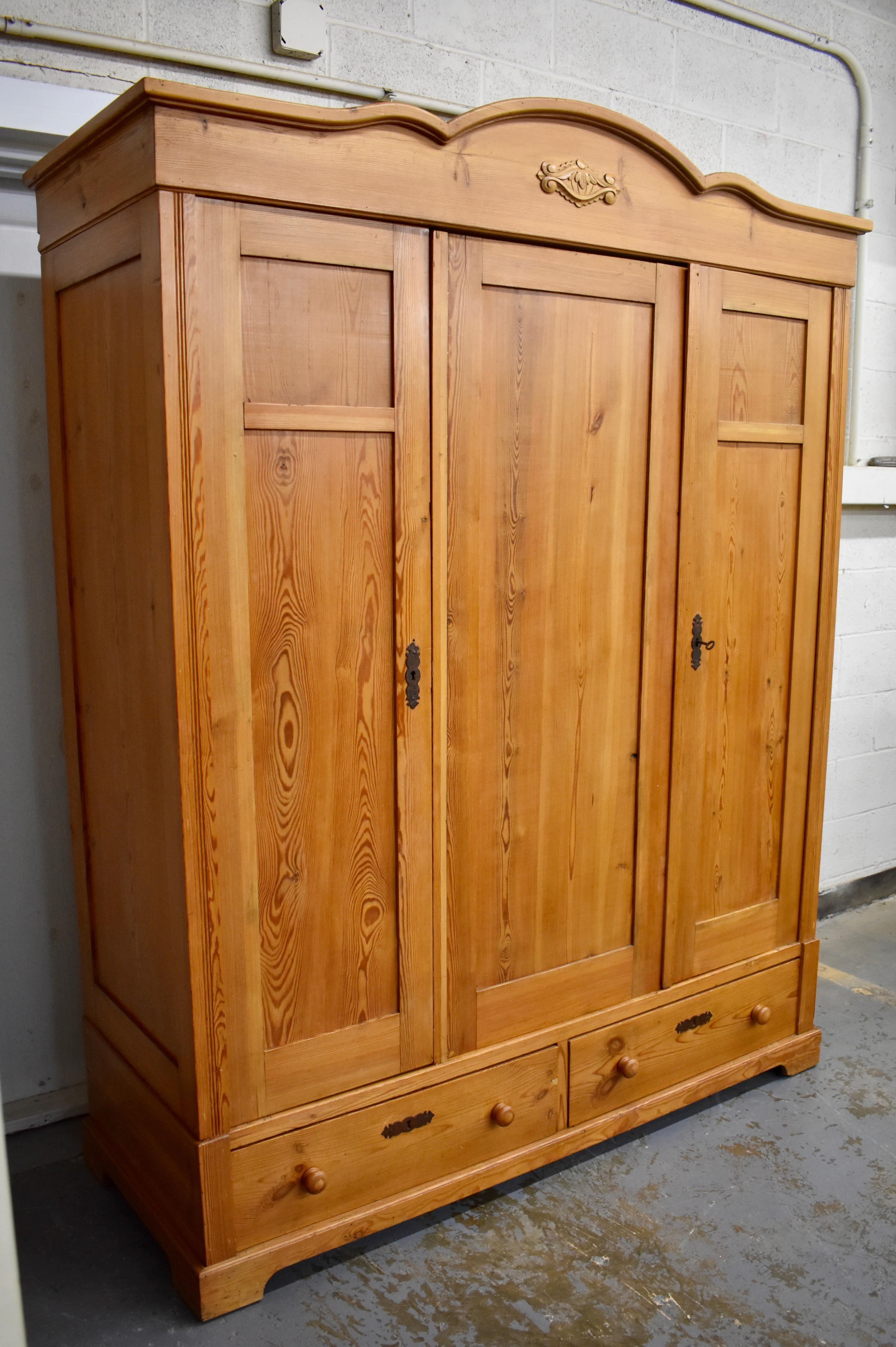This large, three door armoire has minimal decoration beyond the crown, with its scalloped molding and applied medallion. The rest is plain and simple and very attractive, only an excised double reed runs the length of the outside face frame, to