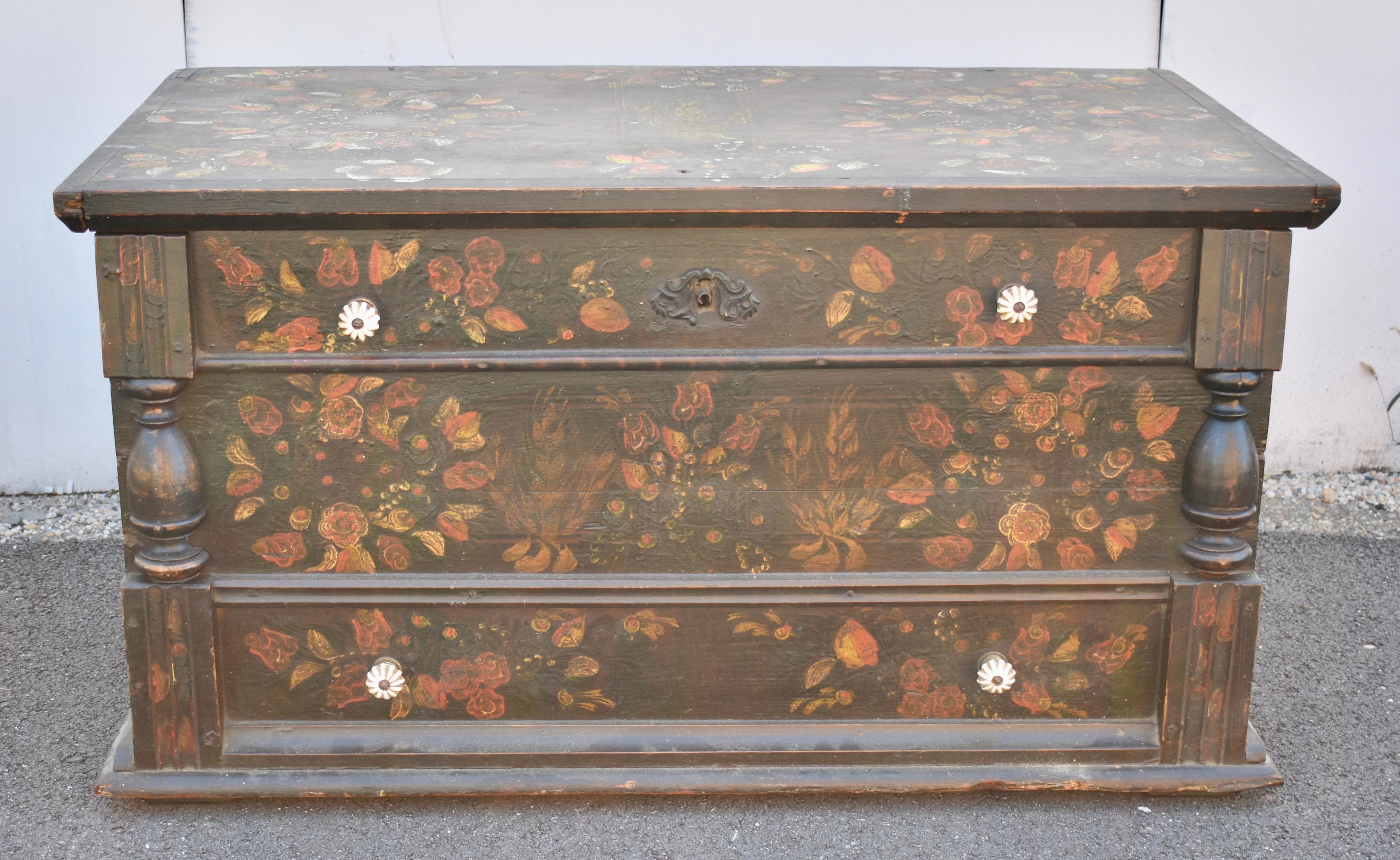 This Folk Art painted trunk has the form of a faux mule chest, pretending to have drawers with ceramic knobs, when, in fact, the lid opens on two very long iron strap hinges to a deep storage well.  In the upper left is a candle box, the hinged lid