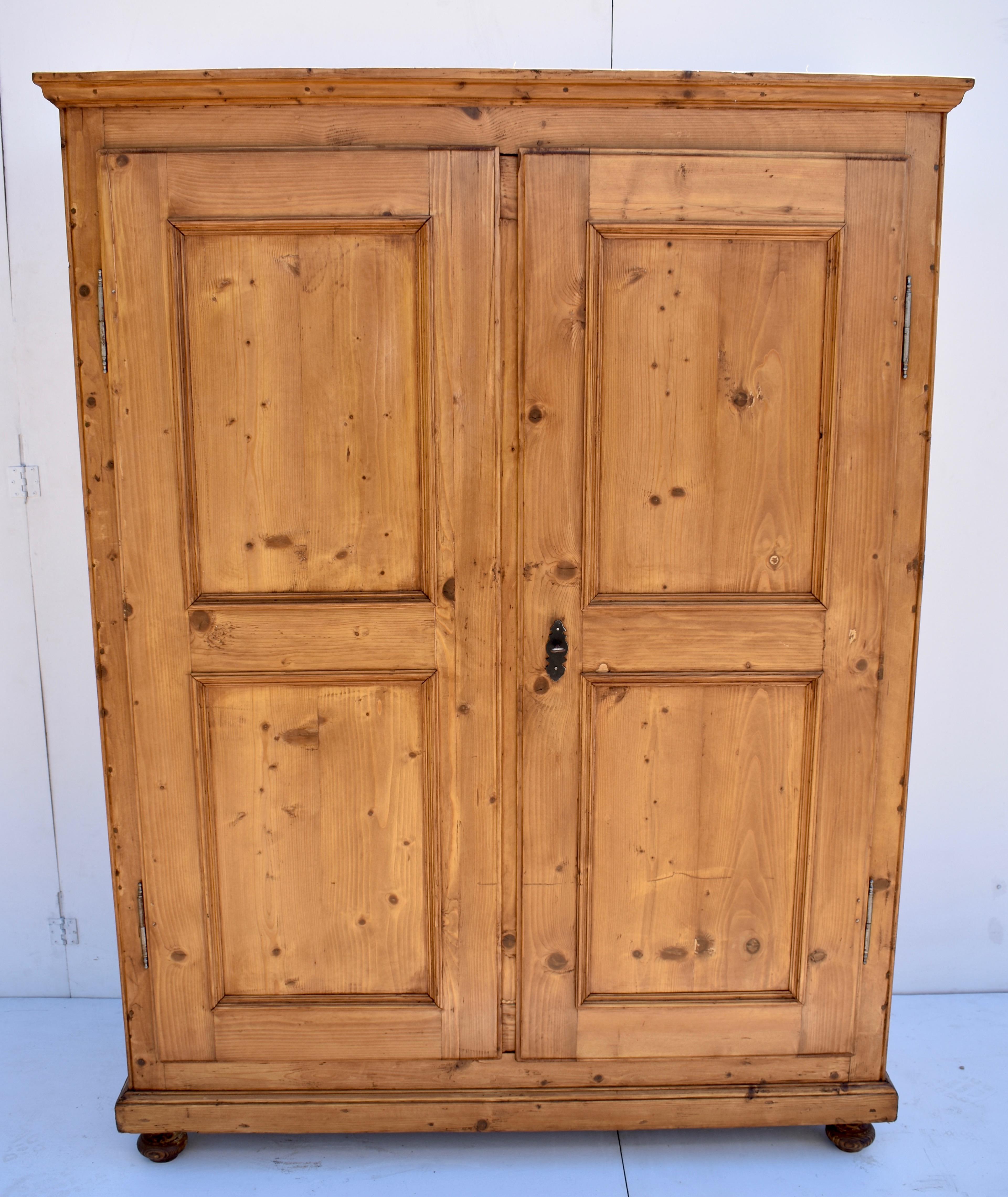 This large pine armoire has a bold ogee crown molding and plain fascia with two paneled doors. The doors have a thumbnail chamfer around the outside of the frame, the only decorative touch apart from a bead carved into the front corners of the case.