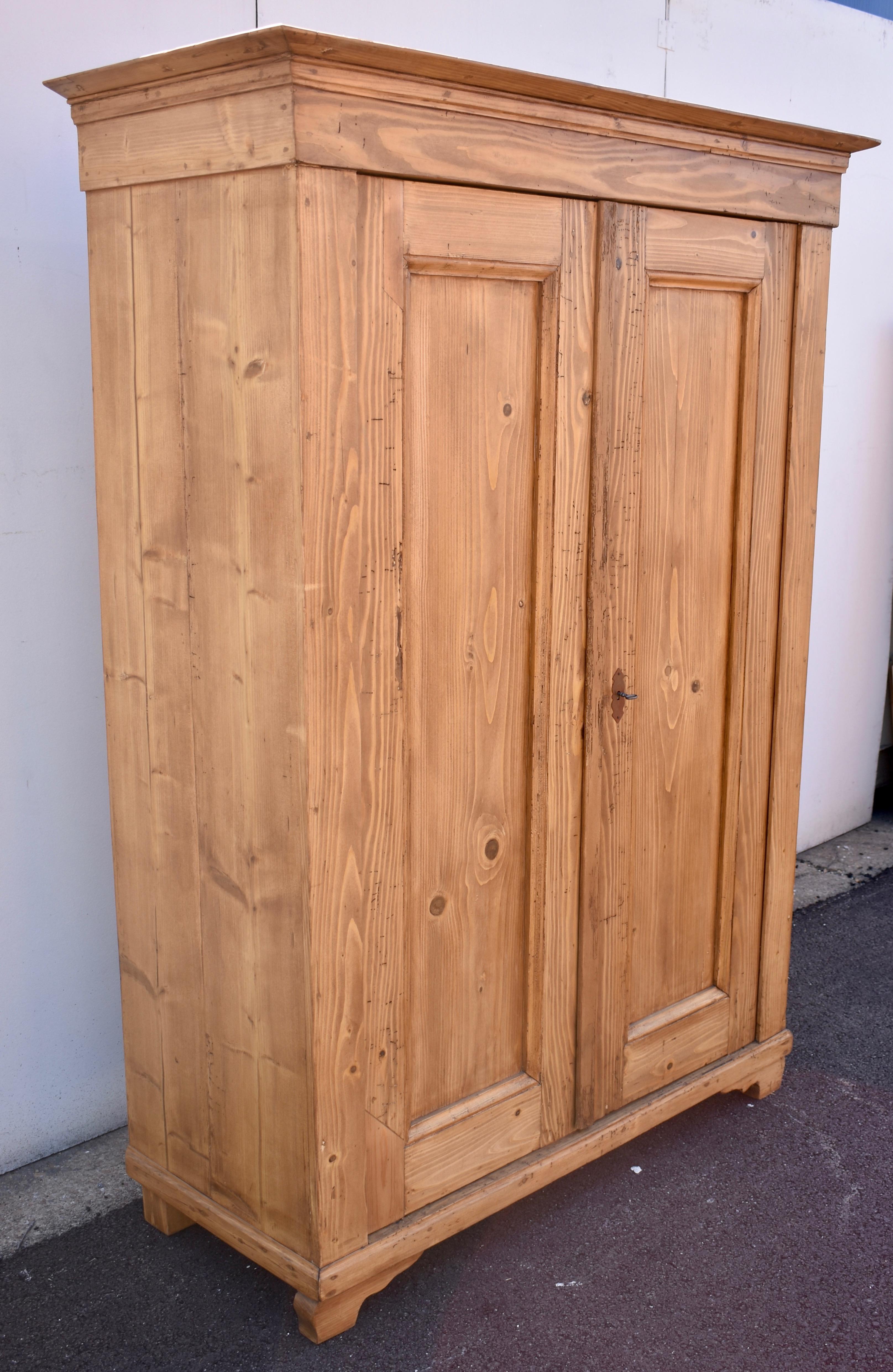 This relatively plain and simple armoire is an early piece, well-built from heavy stock with a strong grain pattern.  Mortise and tenon joints, moldings and trim, are secured with wooden pegs, as is the primitive crown.  The doors open on pivot