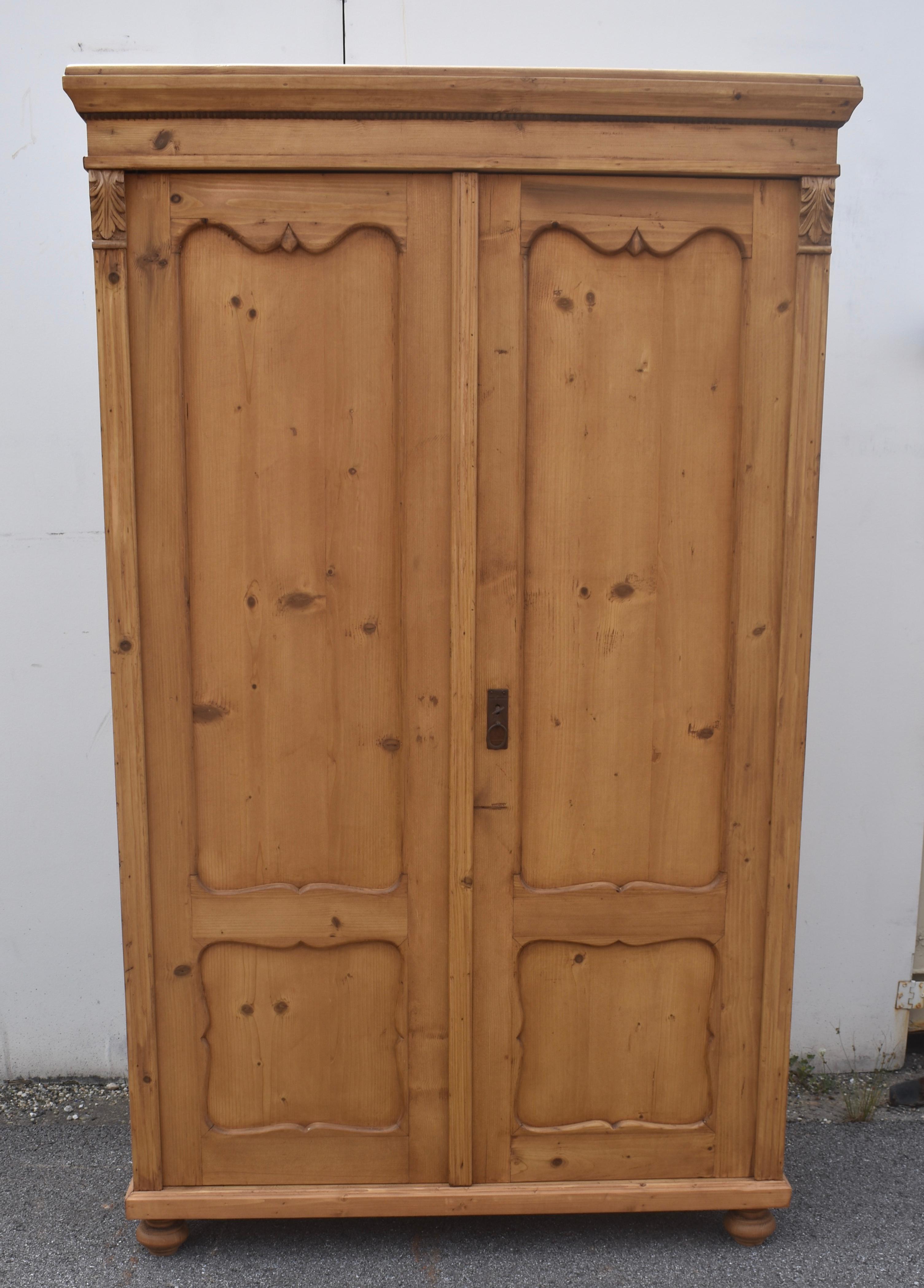 This sturdy two door armoire has a heavy hand-planed crown molding above a plain frieze and bead.  The two doors each have one long and one short panel.  The rails and stiles of the door frames are scalloped in the Dutch style and the front corners