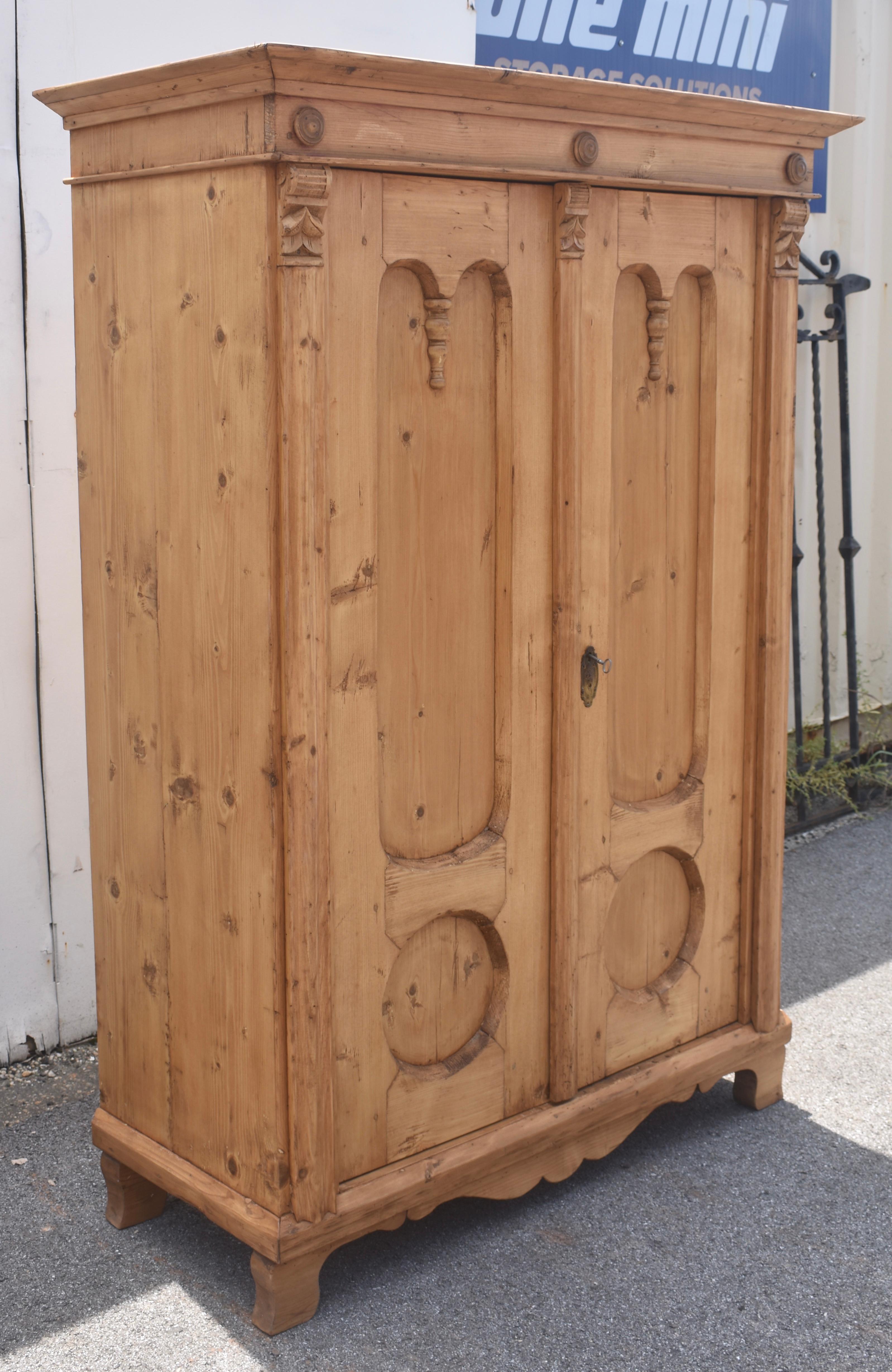 Built from heavier stock than most, and with a beautiful color and lots of character, this sturdy little two door armoire is unusual and interesting.  The crown is plain, like those on Irish dressers.  The frieze beneath is adorned with three